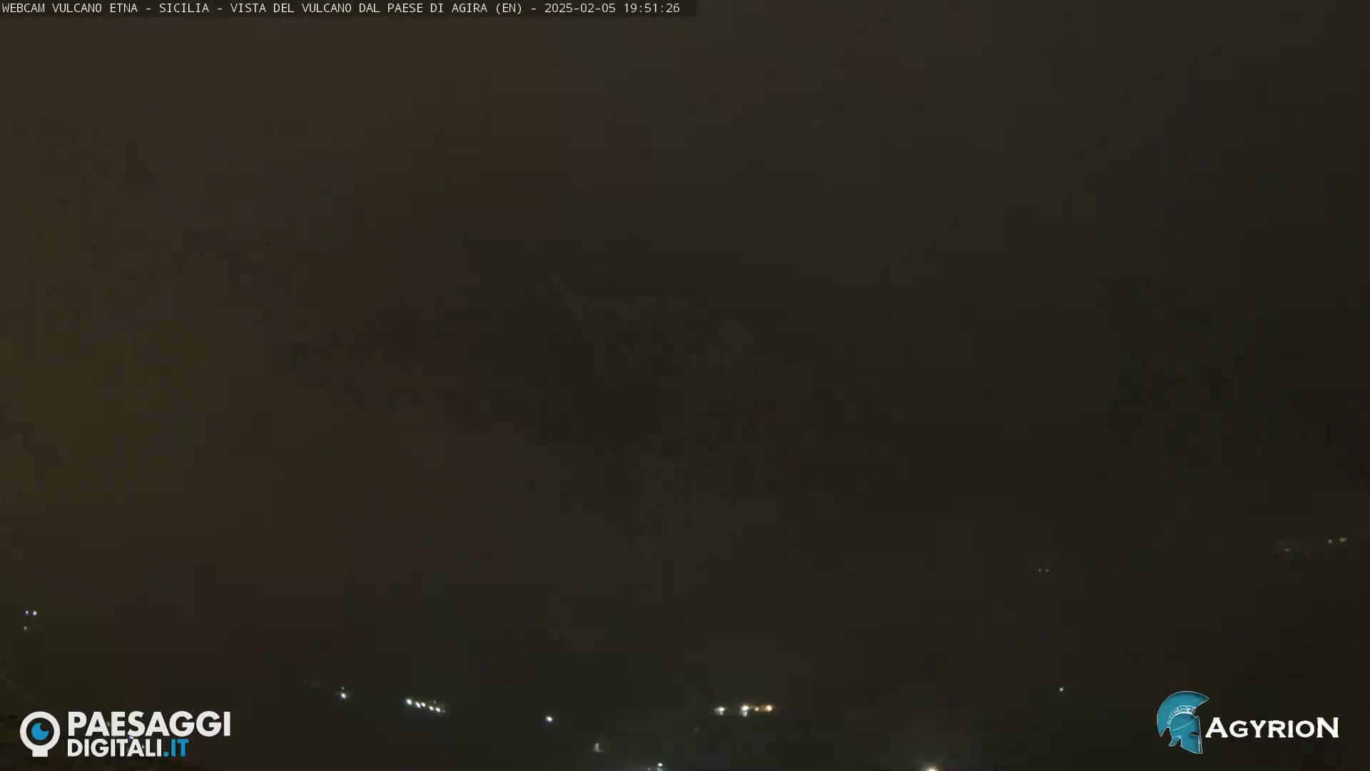 A dark, hazy night scene shows distant, faint lights along the horizon.