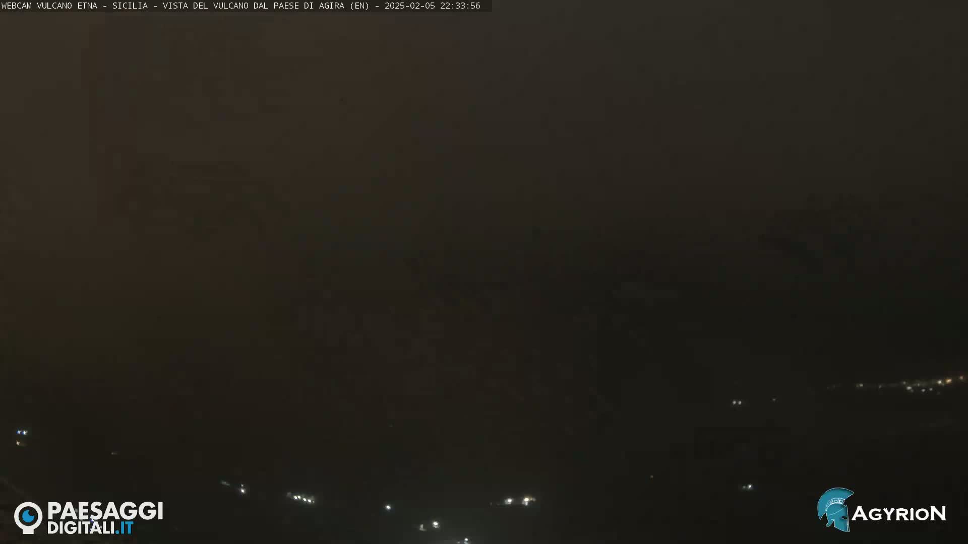 A dark, hazy night scene shows a few faint lights in the distance.