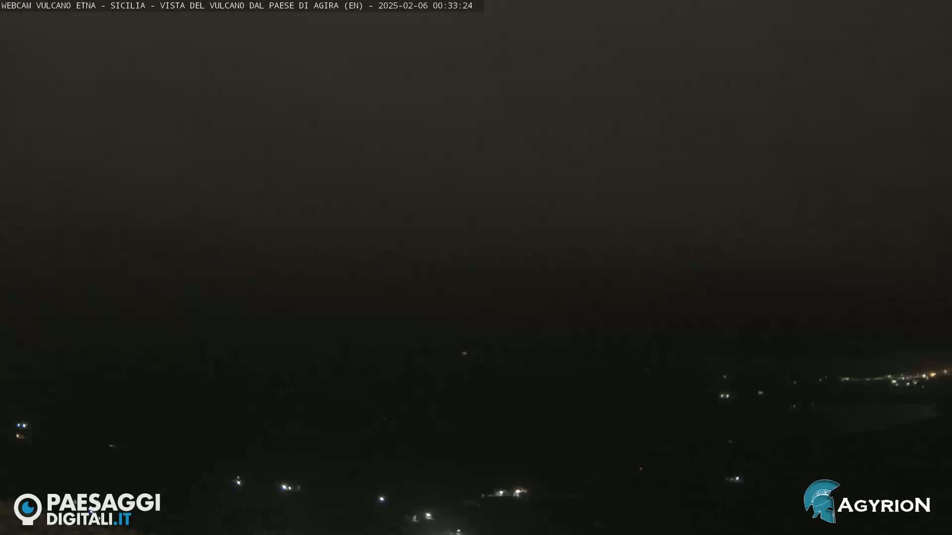 A nighttime, hazy long shot shows a dark landscape with a few distant lights.