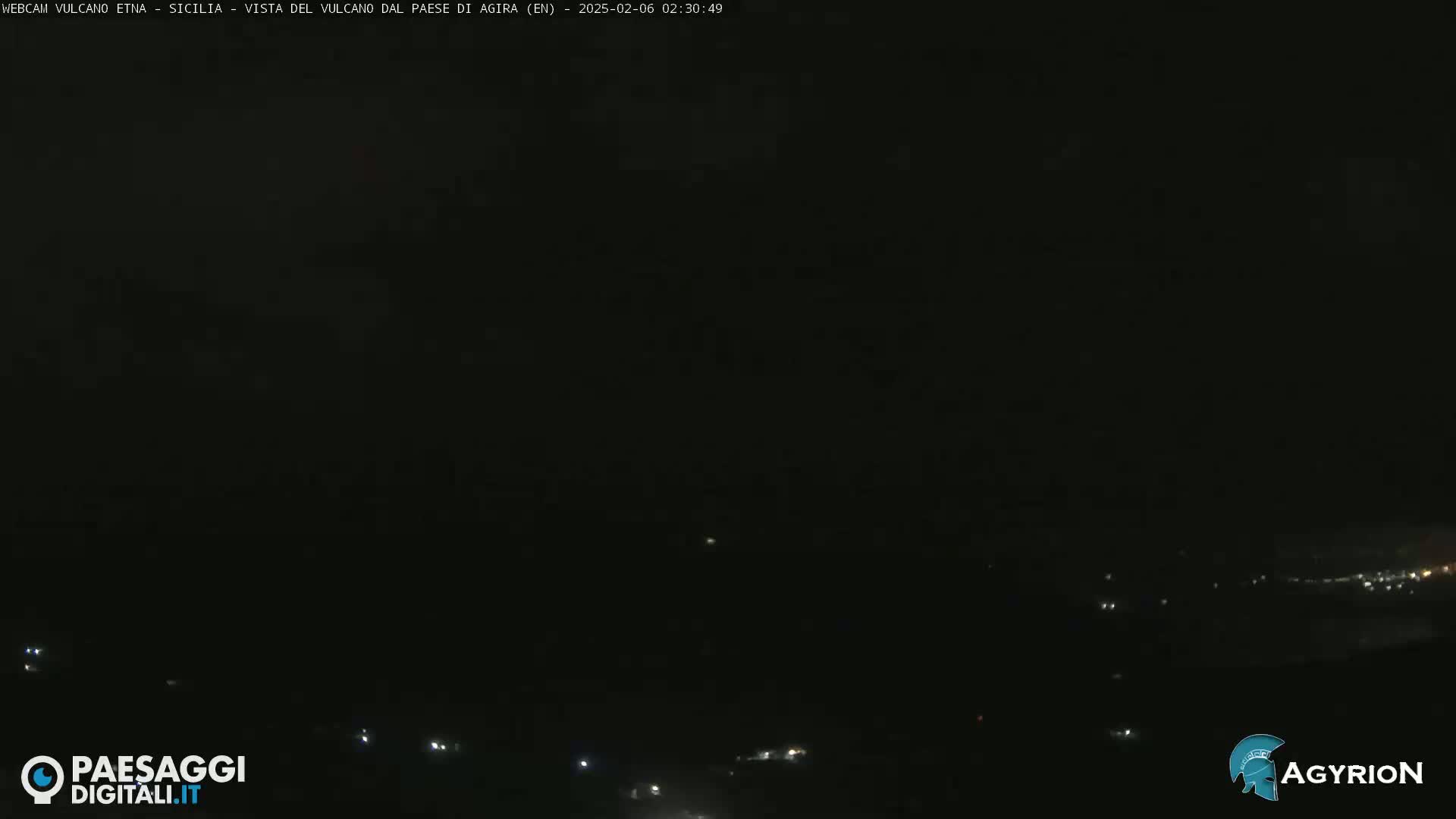 A dark, nighttime view of a distant, dimly lit landscape.