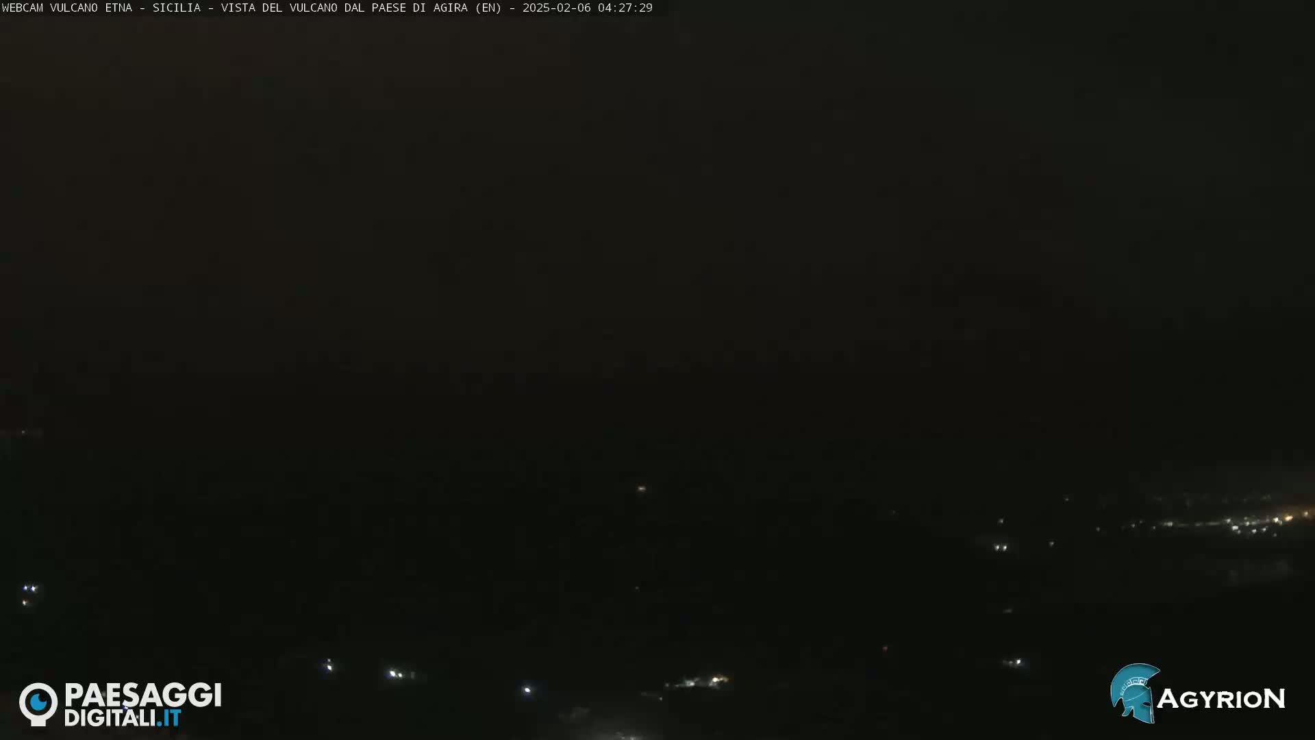 A dark, nighttime view of a distant, dimly lit landscape.