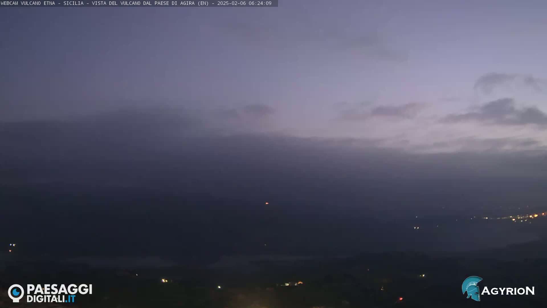 A hazy, low-light view of a distant landscape under a mostly cloudy sky.