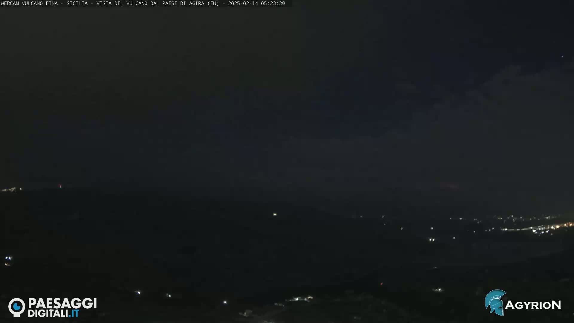 A nighttime long shot of a dark, sparsely lit landscape under a mostly clear sky.