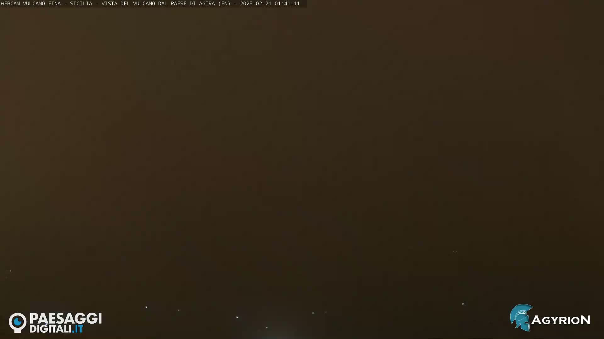 A dark, hazy, outdoor scene is visible at night, with a few faint lights in the distance.