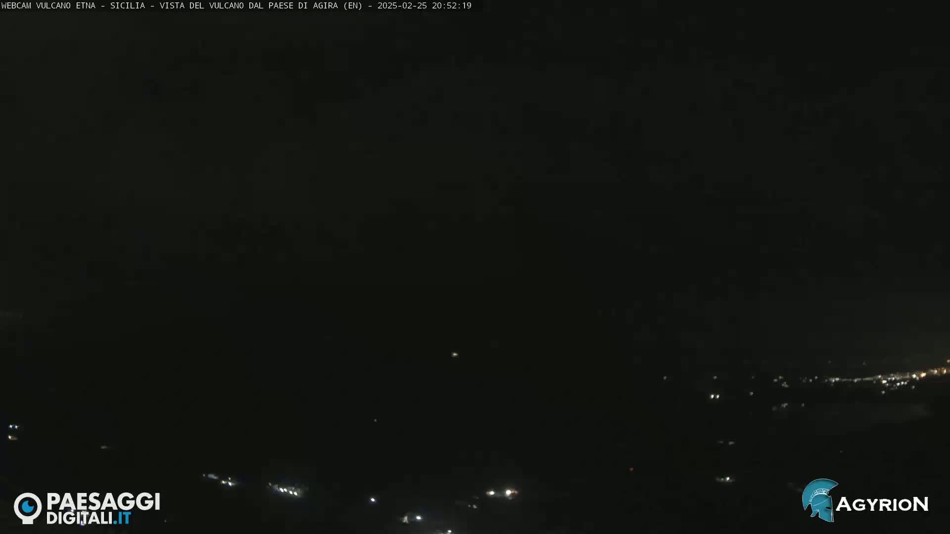 A dark nighttime view of a distant town with scattered lights, under a clear, black sky.
