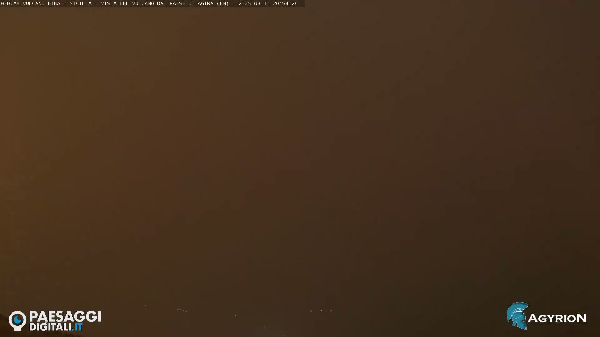 A hazy, dark brown landscape is visible under a dusky sky.