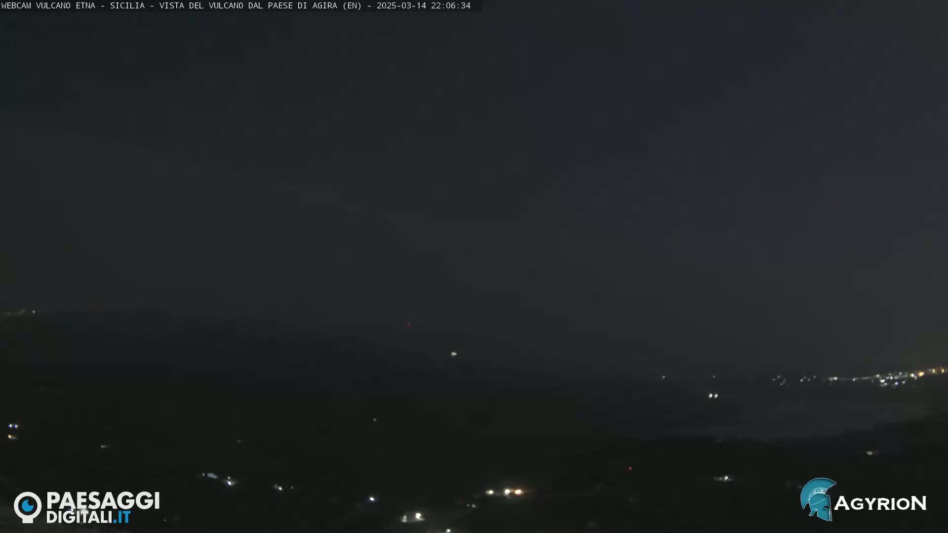 A nighttime, dark, and hazy view of a distant town and landscape.