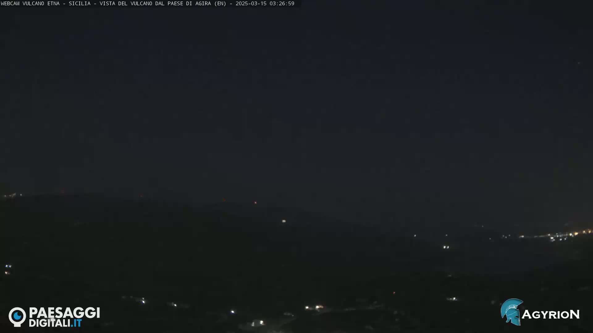 A nighttime long shot of dimly lit hills and a dark sky.