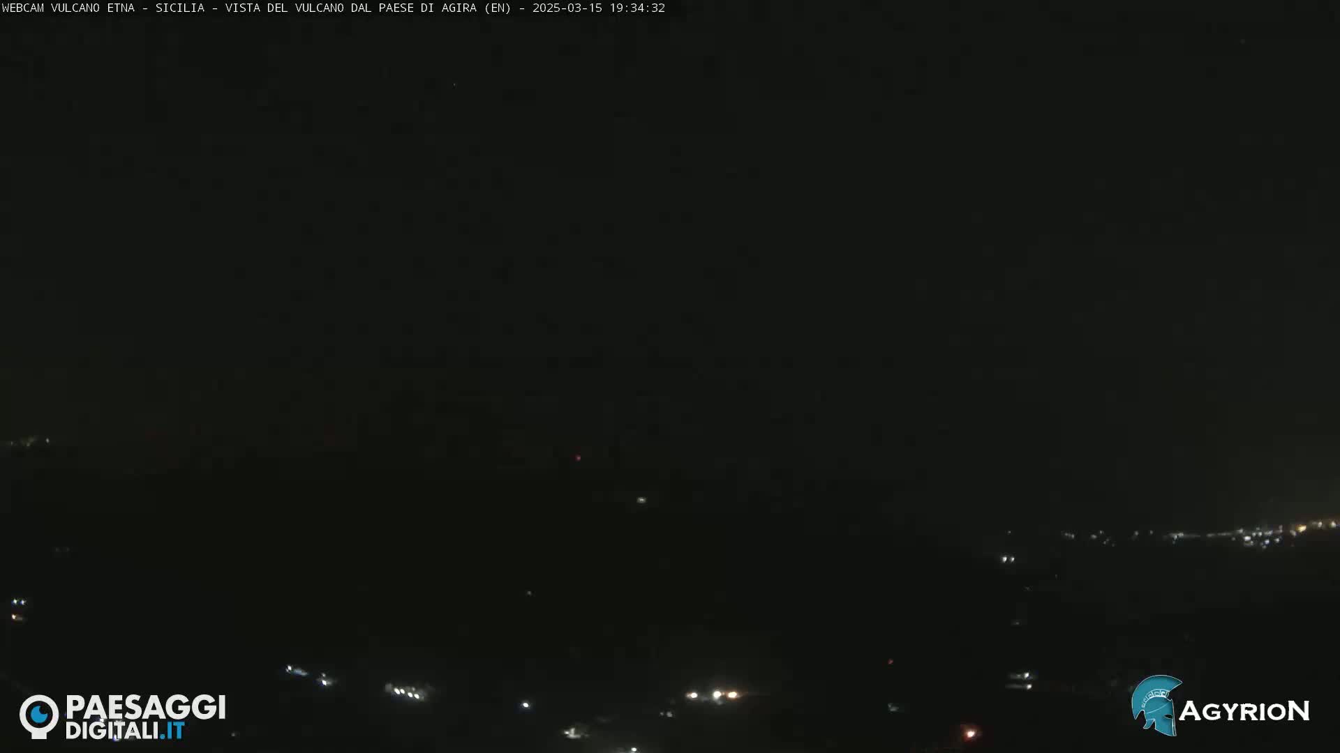 A nighttime, dark view of a city or town illuminated by scattered lights.