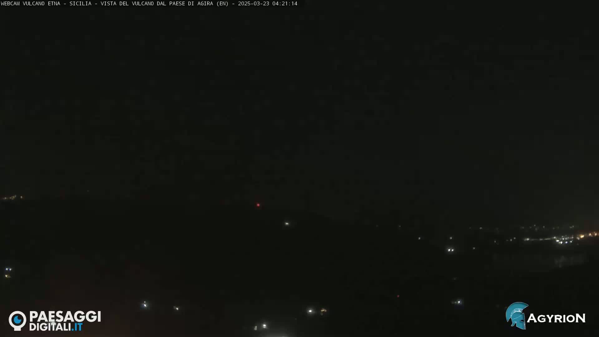 A nighttime, dark view of a distant town with scattered lights under a clear, dark sky.