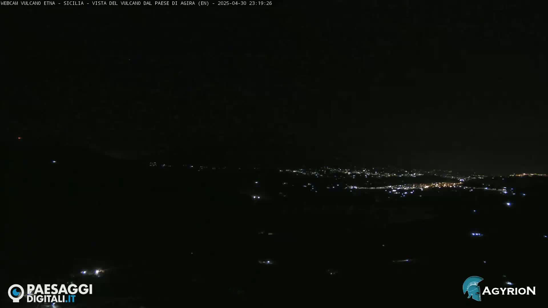 A nighttime long shot shows a dark landscape with a distant town illuminated by scattered lights.