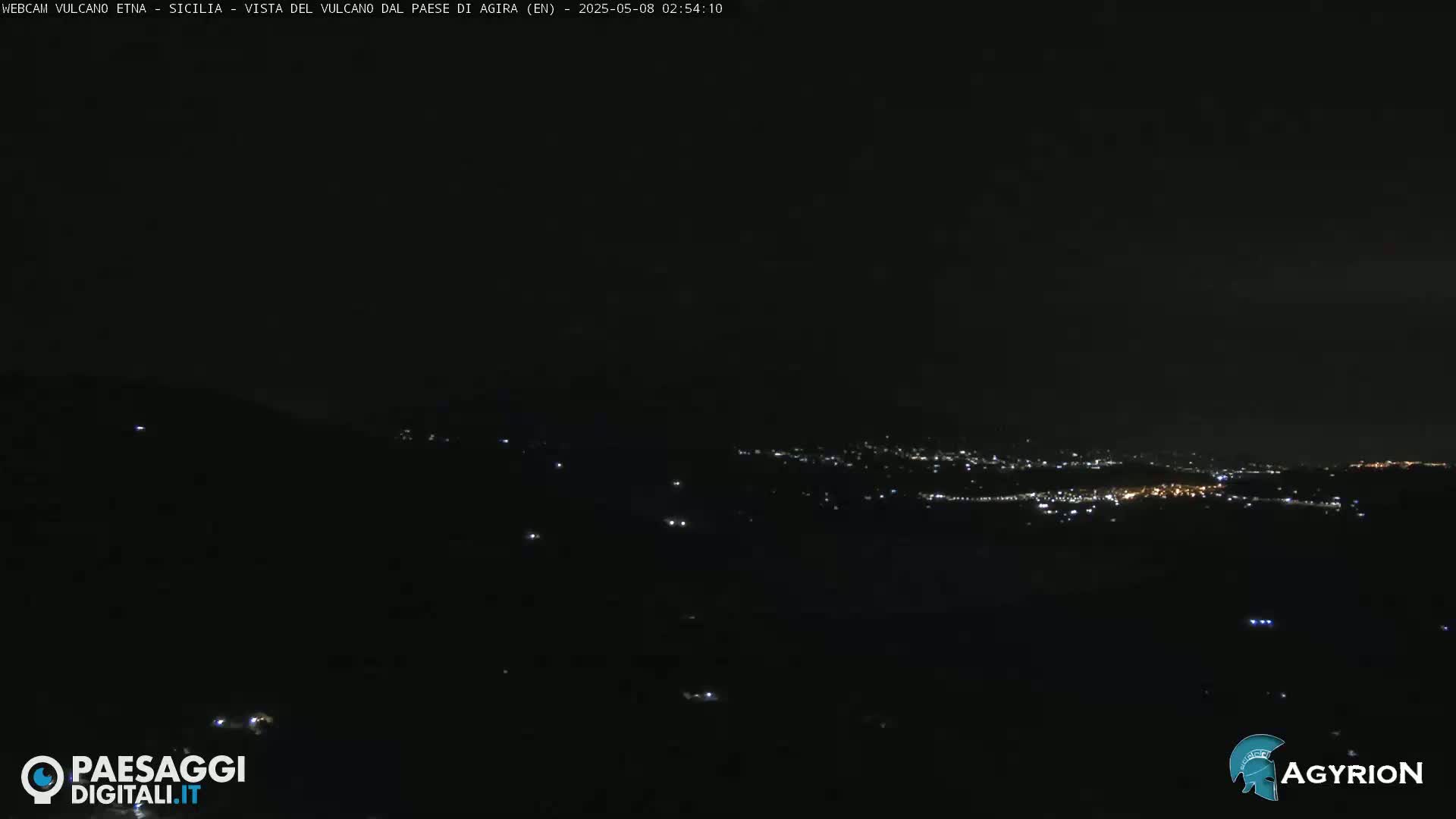 A nighttime, long-range view of a city's lights spread across a dark valley.