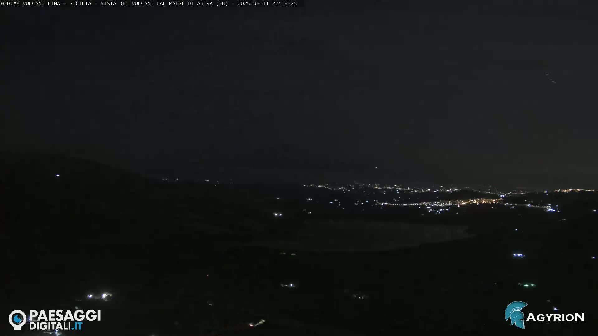 A nighttime view shows a distant city illuminated below a dark sky.