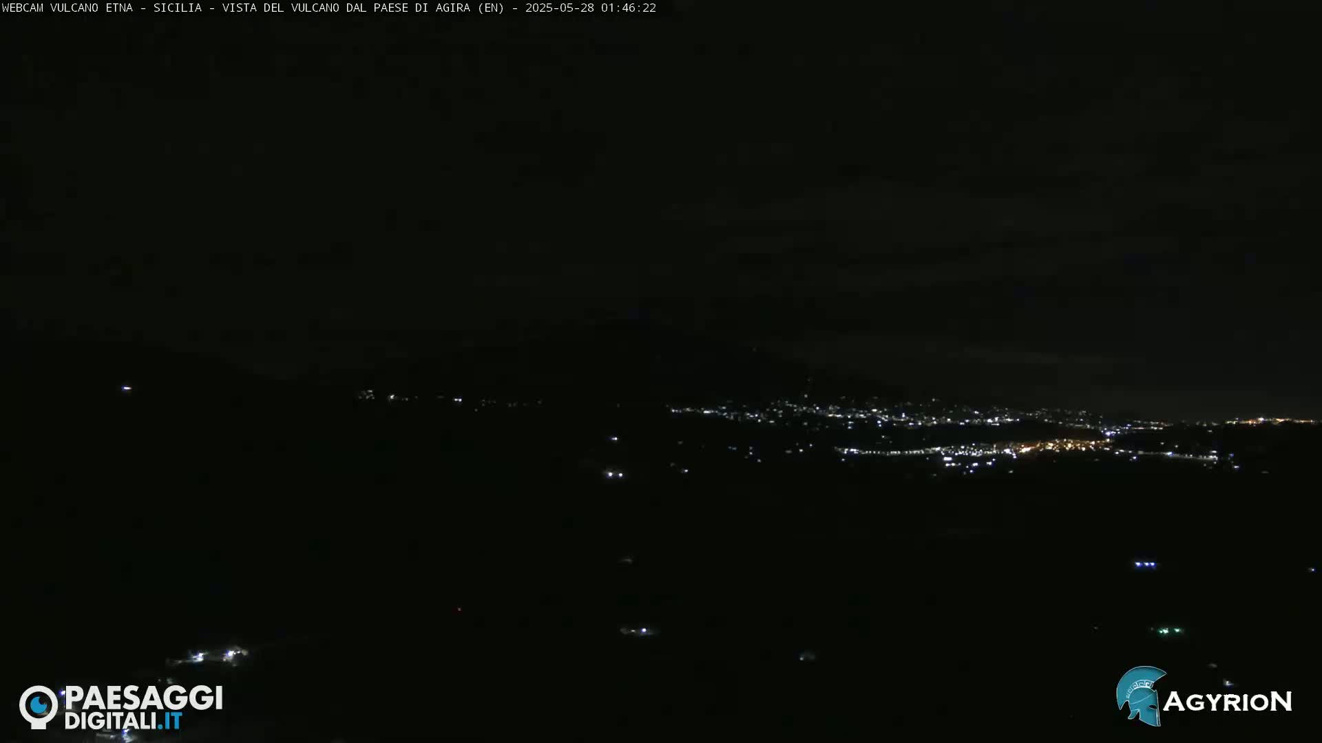 A nighttime, long-range view of a city's lights spread across a dark landscape under a mostly clear sky.