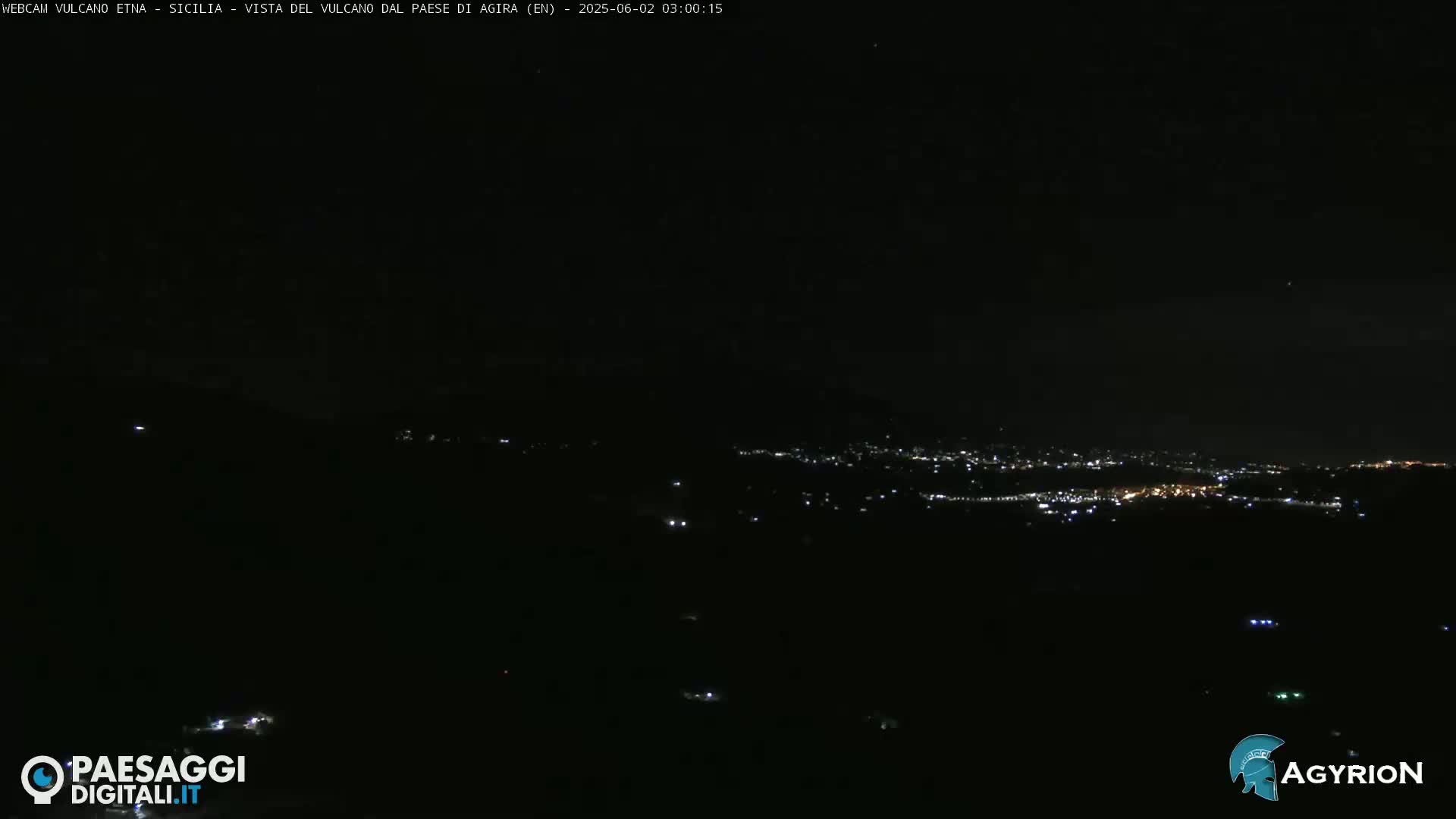 A nighttime, long-distance view of a city's lights spread across a dark landscape.