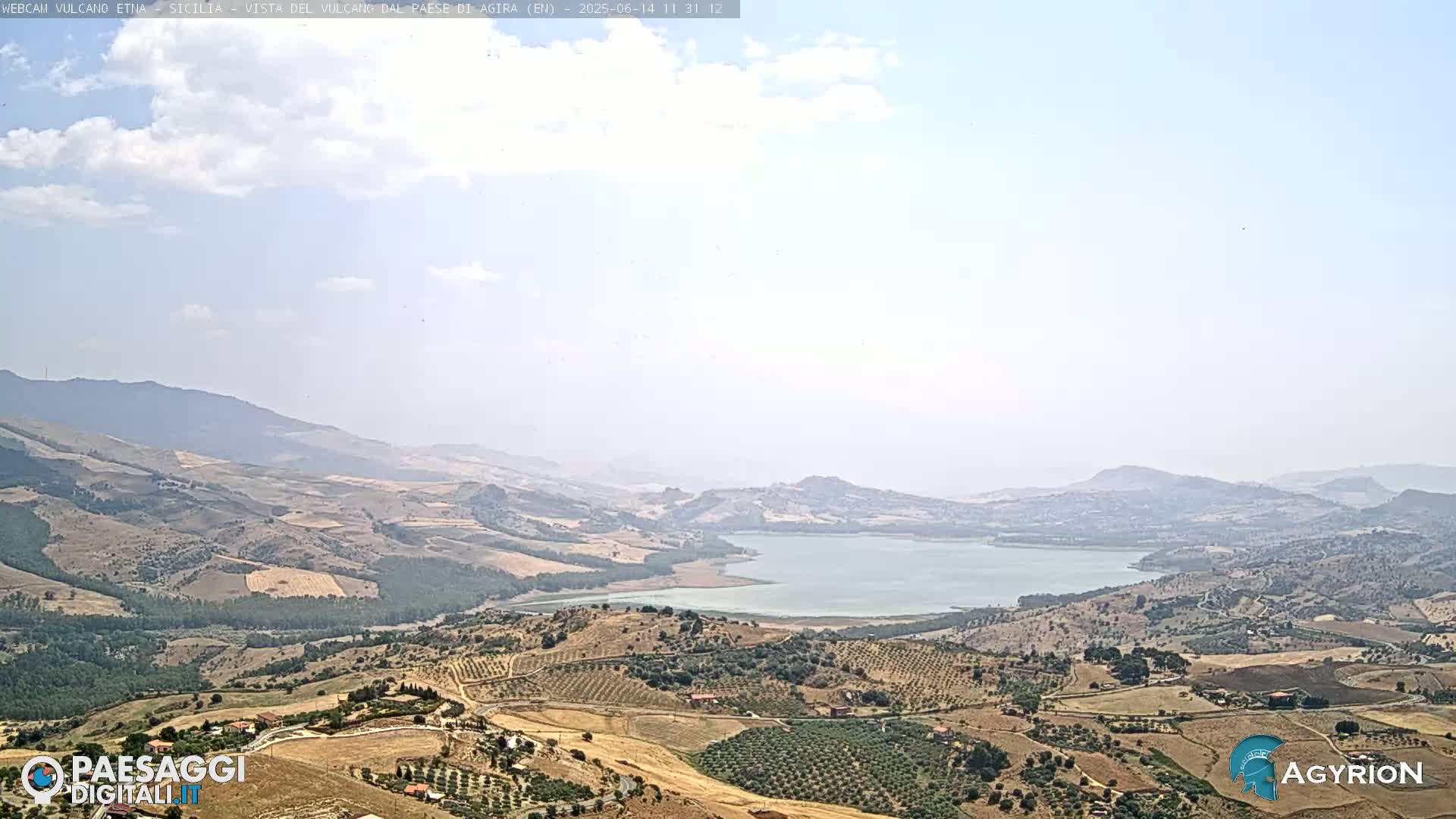 A vast, hilly landscape with a lake is visible under a mostly clear sky.