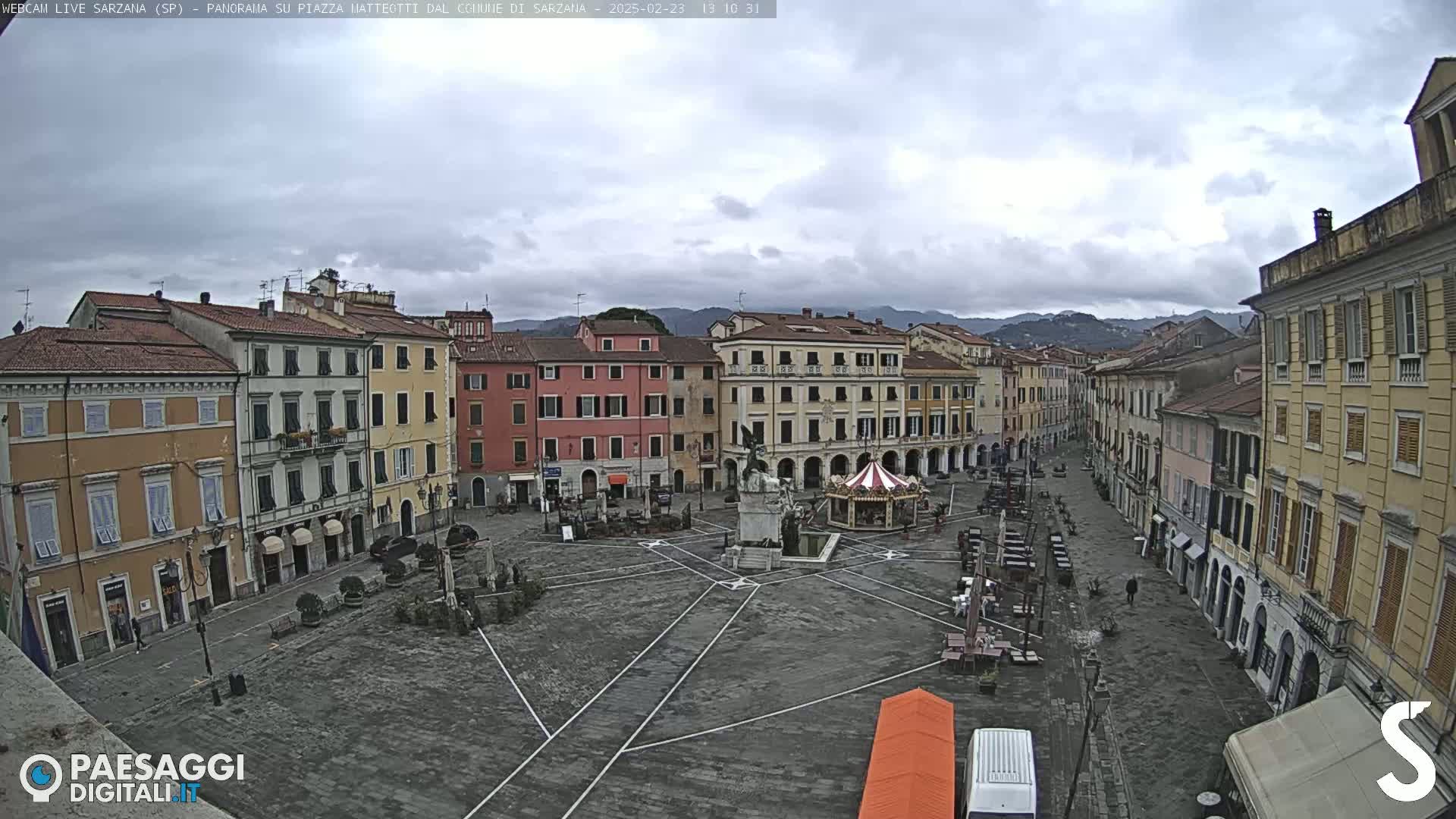 A large, mostly empty town square surrounded by multi-story buildings under an overcast sky.