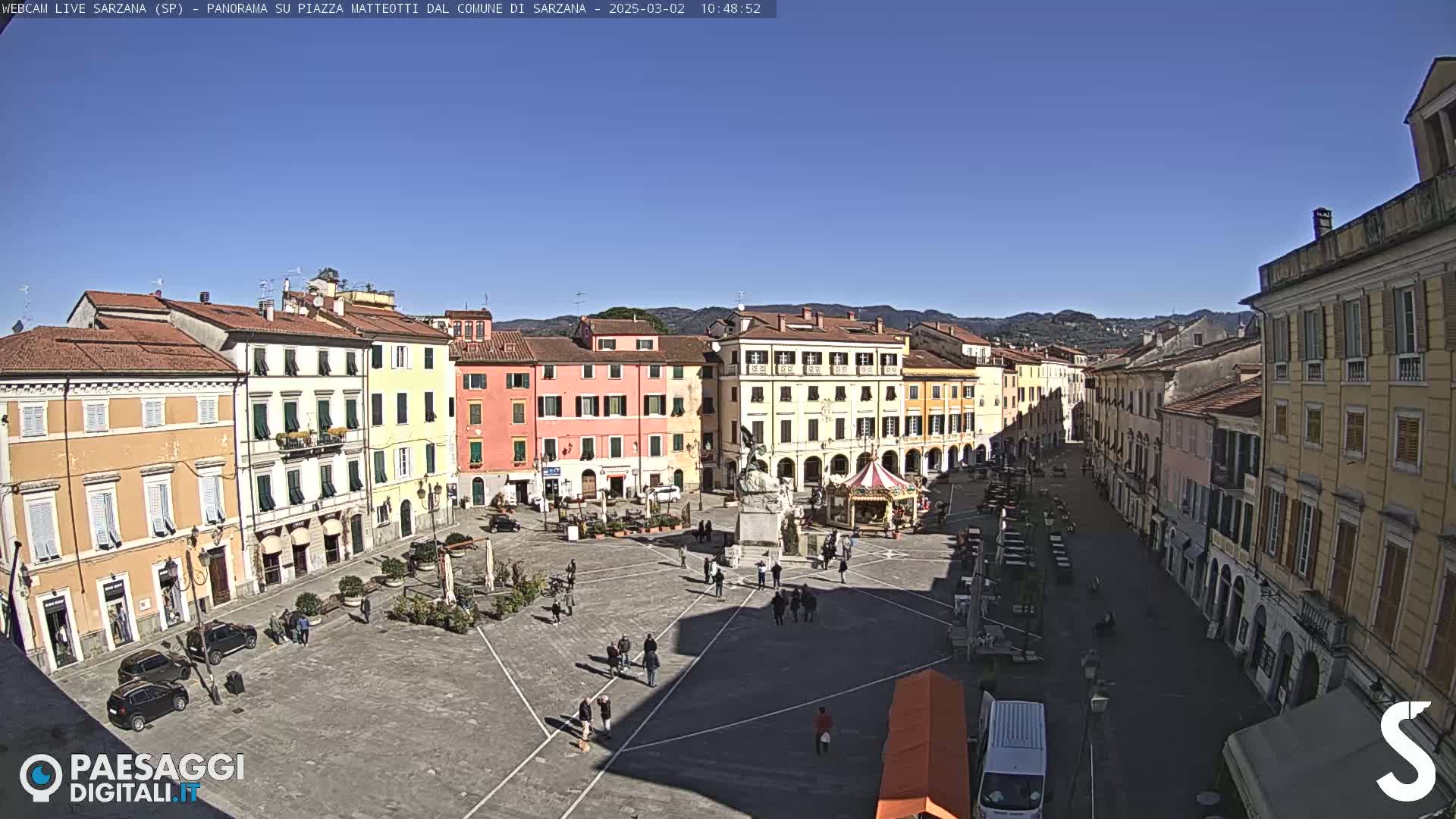 A large town square with colorful buildings surrounding it under a clear blue sky.