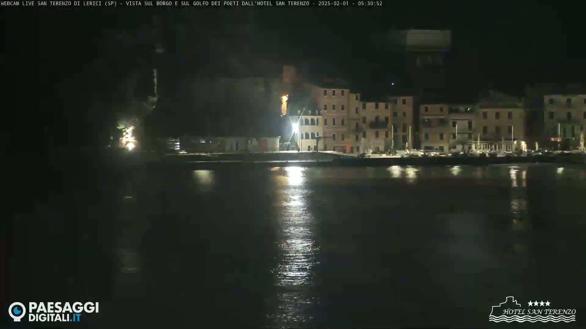 A nighttime view of a calm body of water reflecting the lights of a waterfront town.