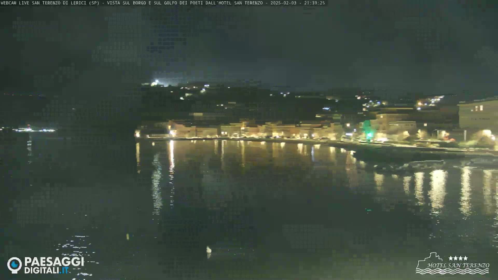 A nighttime view of a calm body of water reflecting the lights of a town on the opposite shore.