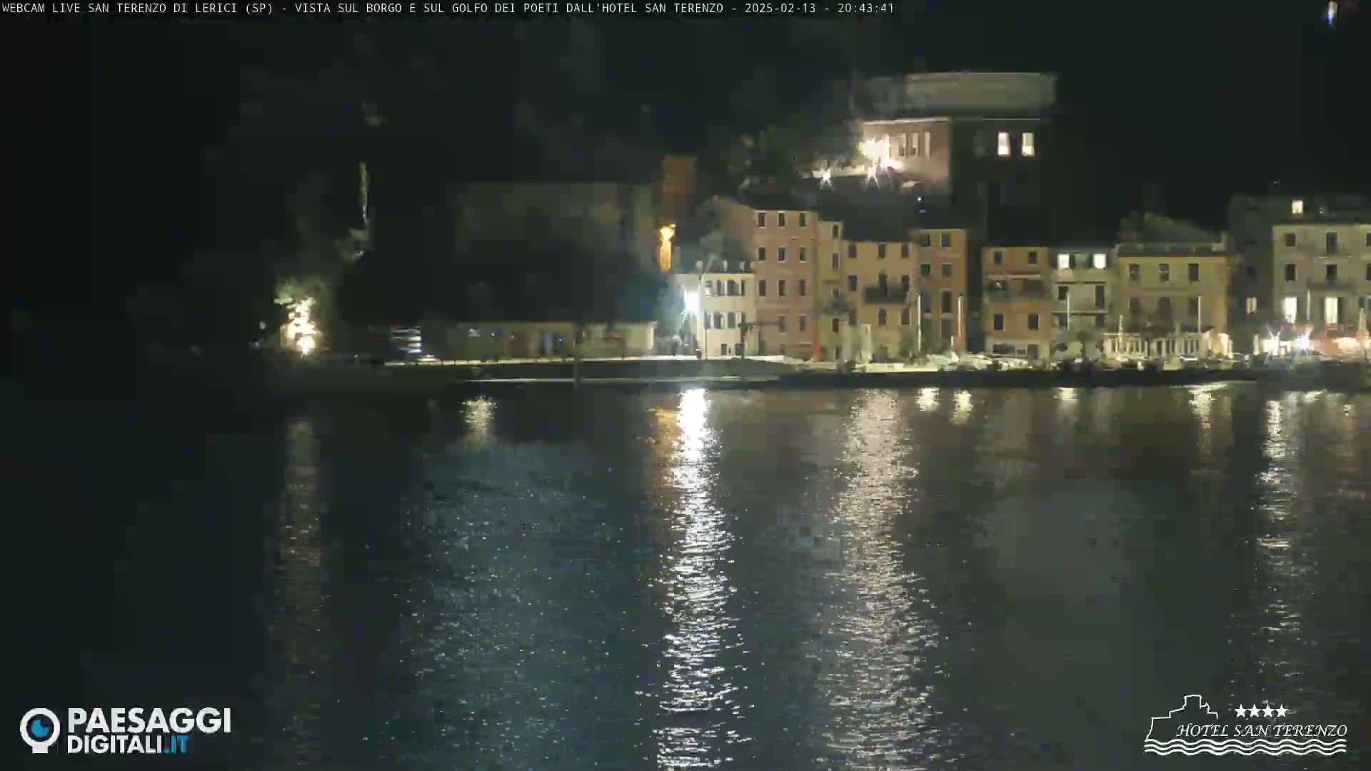 A nighttime view across calm water reflecting lights from a waterfront town.