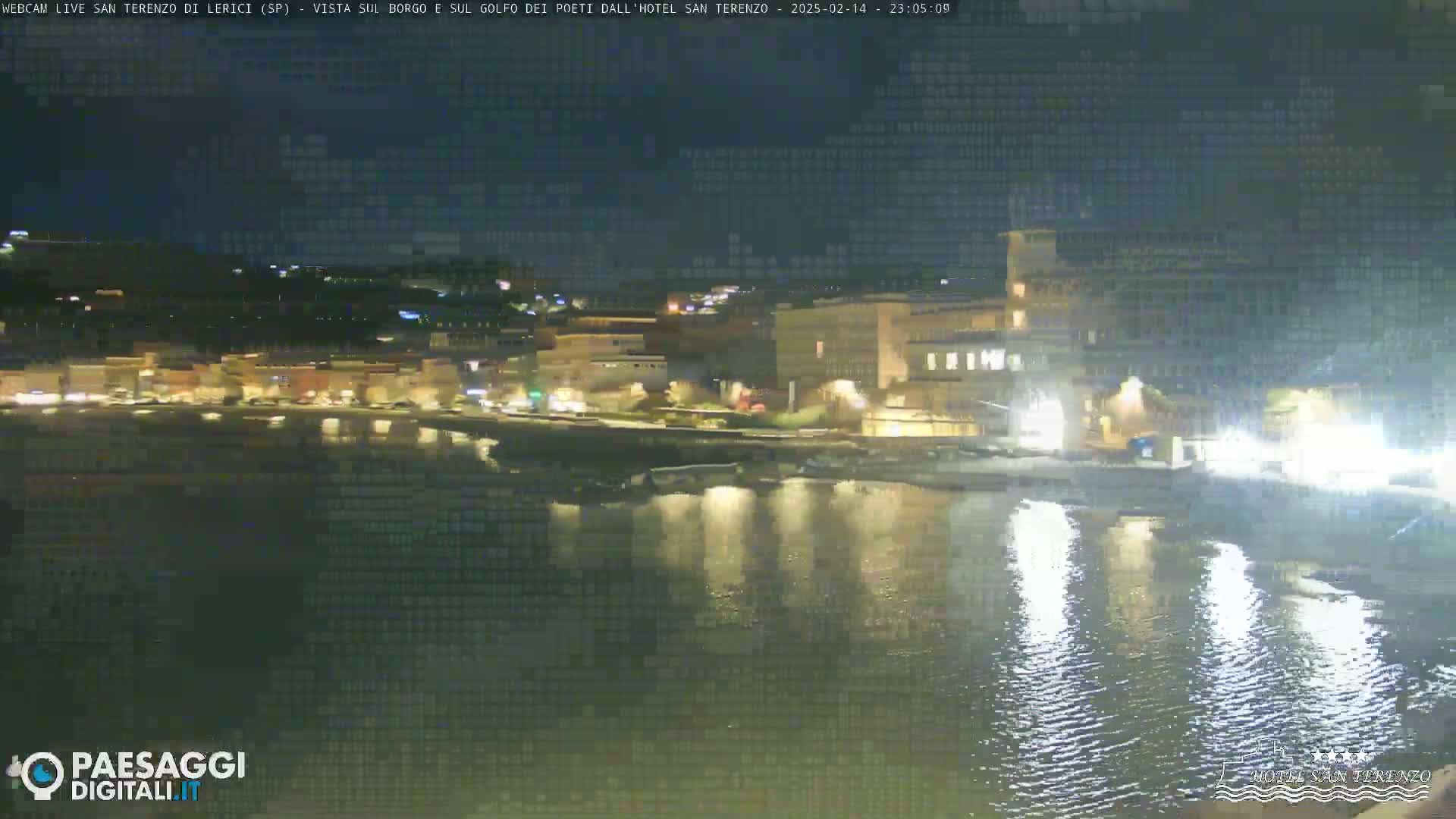 A nighttime view of a waterfront town with lights reflecting on calm water.