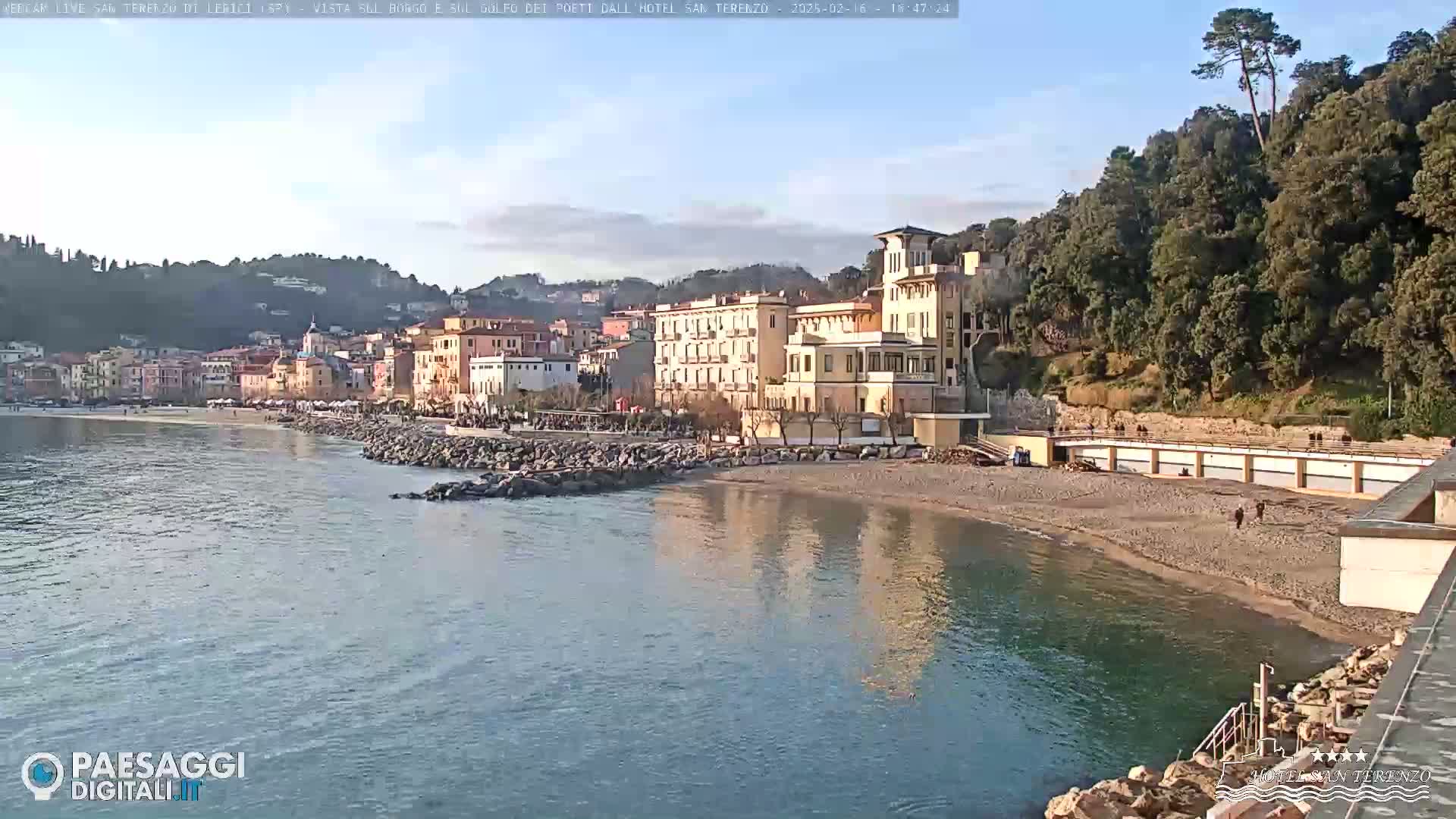 A seaside town with a large hotel and sandy beach is visible under a mostly clear sky.