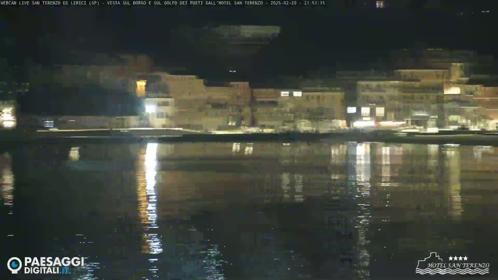A nighttime view of a calm body of water reflecting the lights of buildings along the shore.