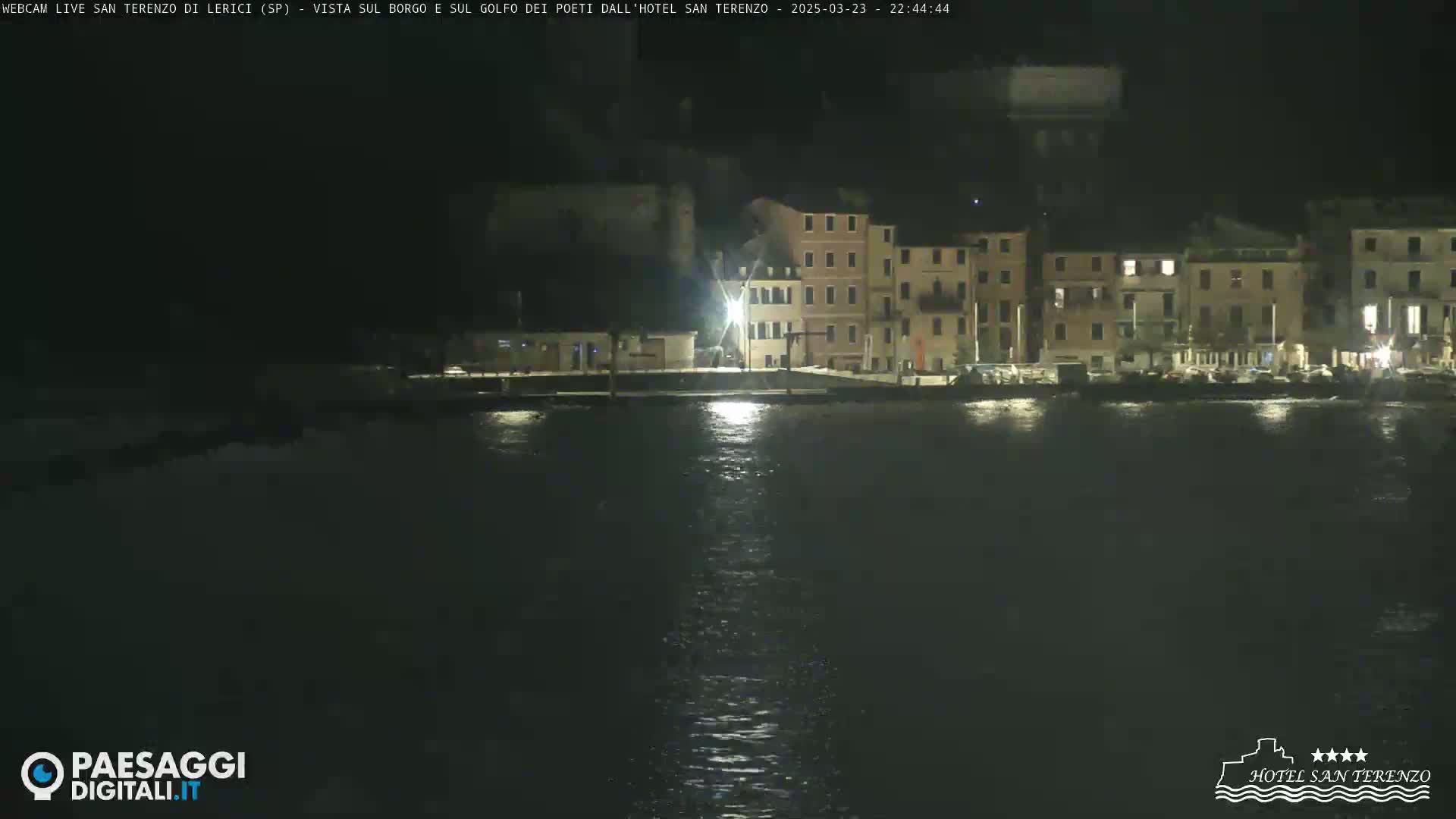 A nighttime view of a calm body of water reflecting the lights of a waterfront town.