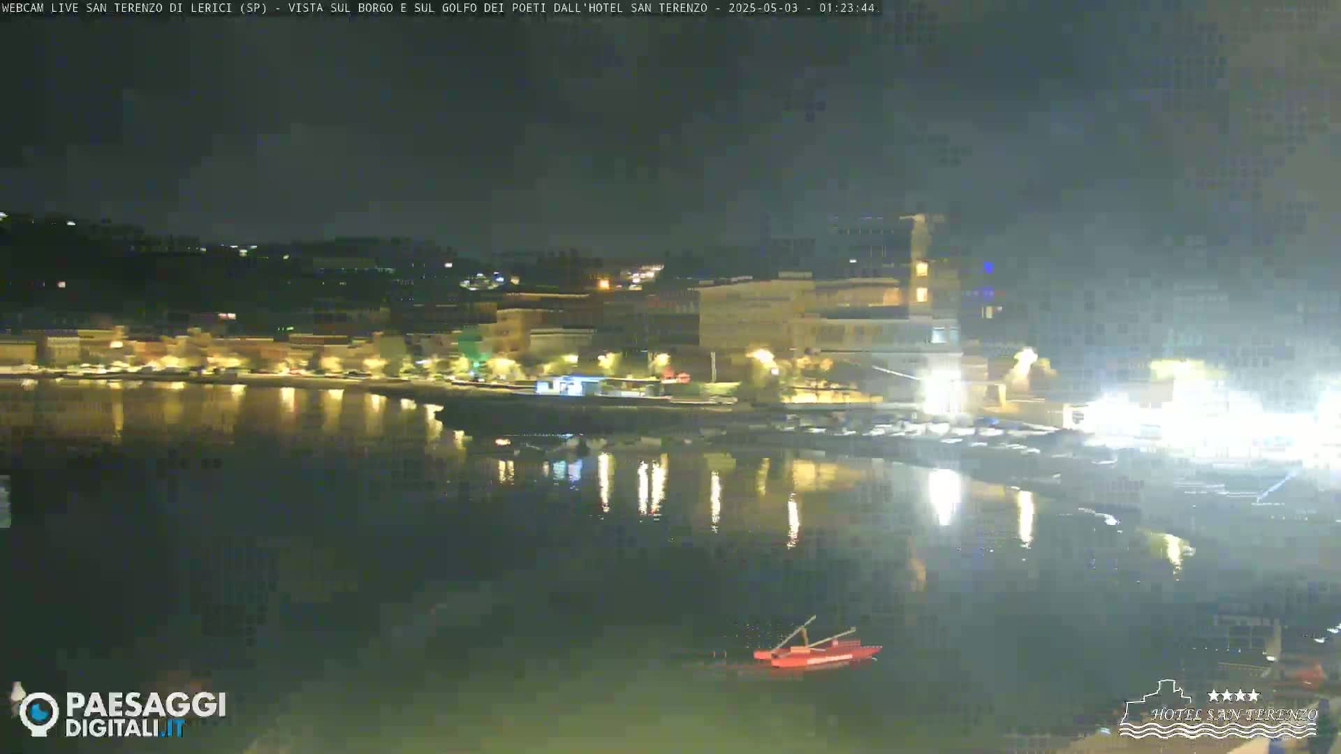 A nighttime view of a calm body of water reflecting the lights of a waterfront town.