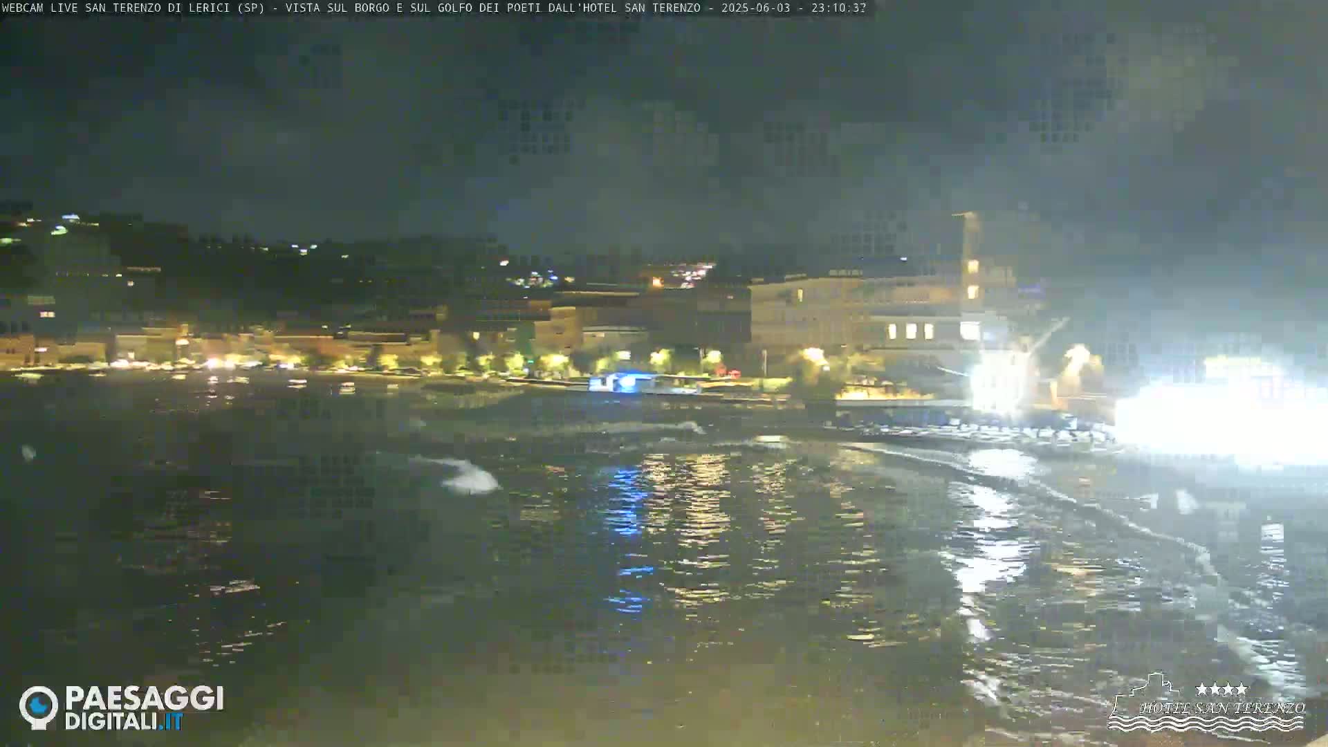 A nighttime view of a calm body of water with lights from buildings and vehicles along the shoreline.