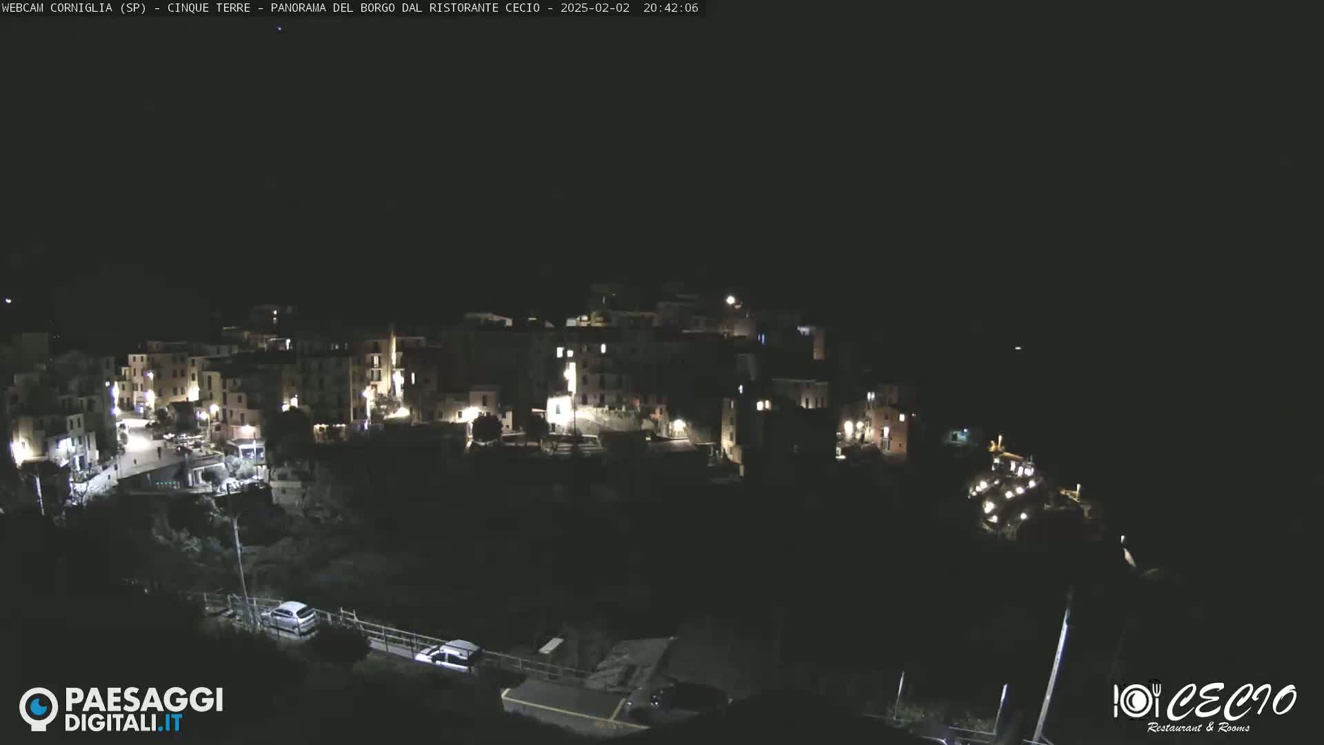 A nighttime aerial view of a small, illuminated town situated on a hillside.