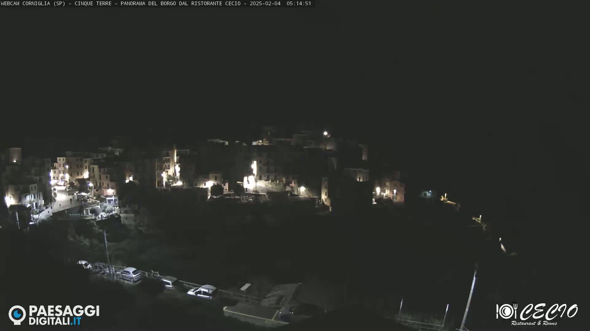 A small, dark village is illuminated by scattered lights at night.