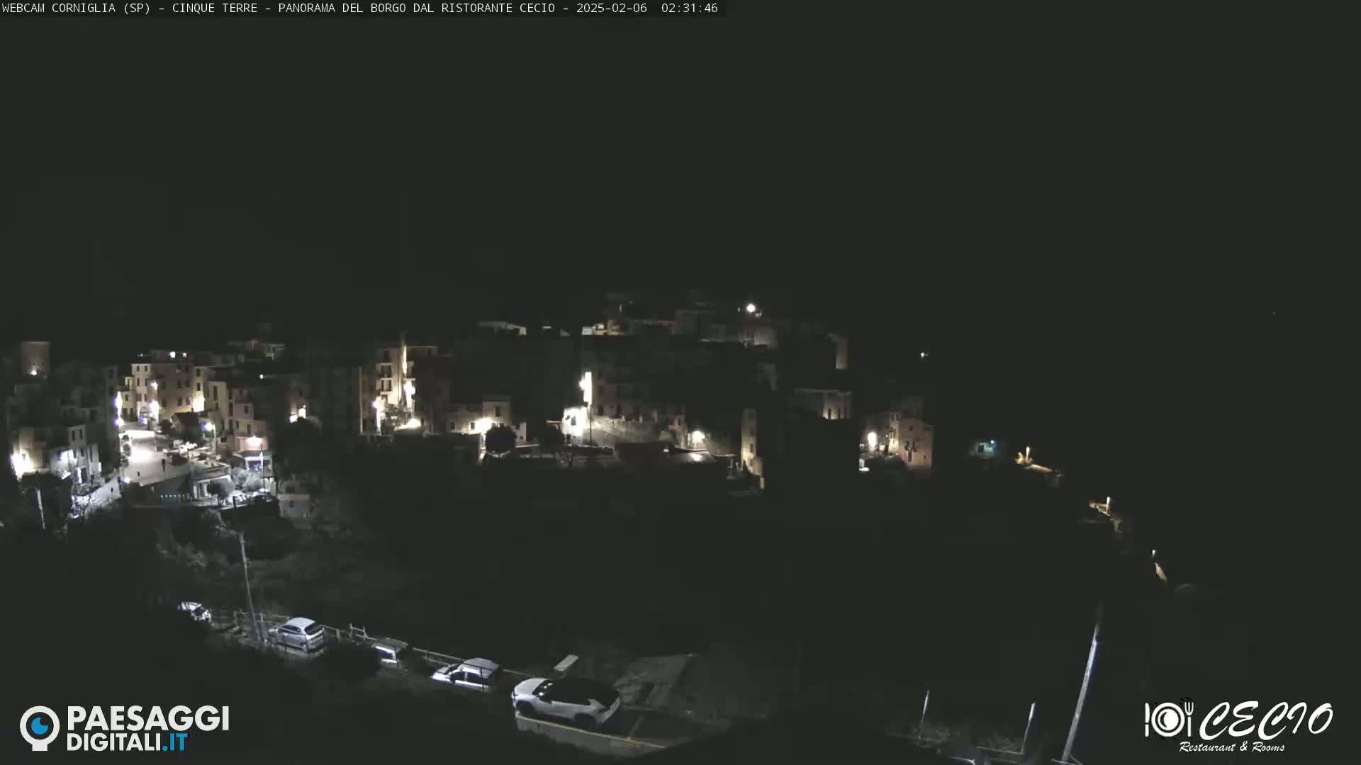 A nighttime, high-angle view of a small, dimly lit town nestled on a hillside.
