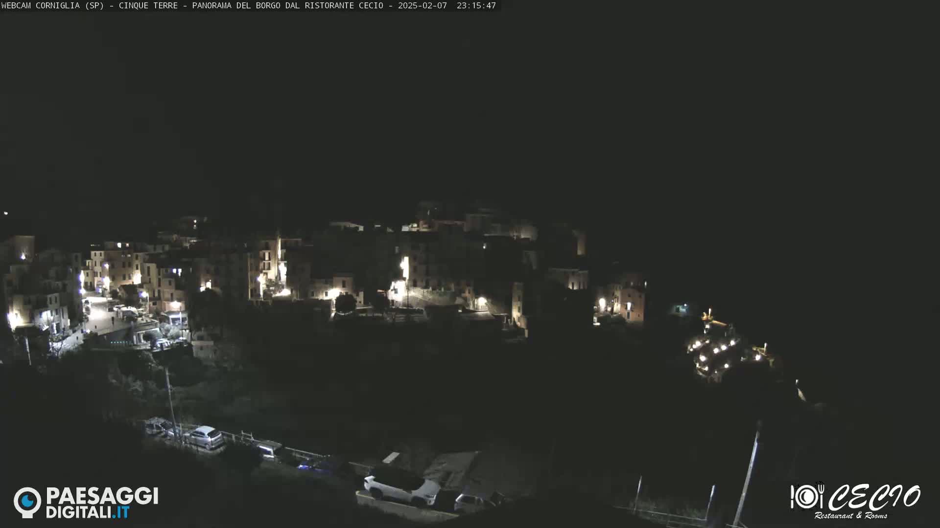 A small, dark village is illuminated by scattered lights at night.