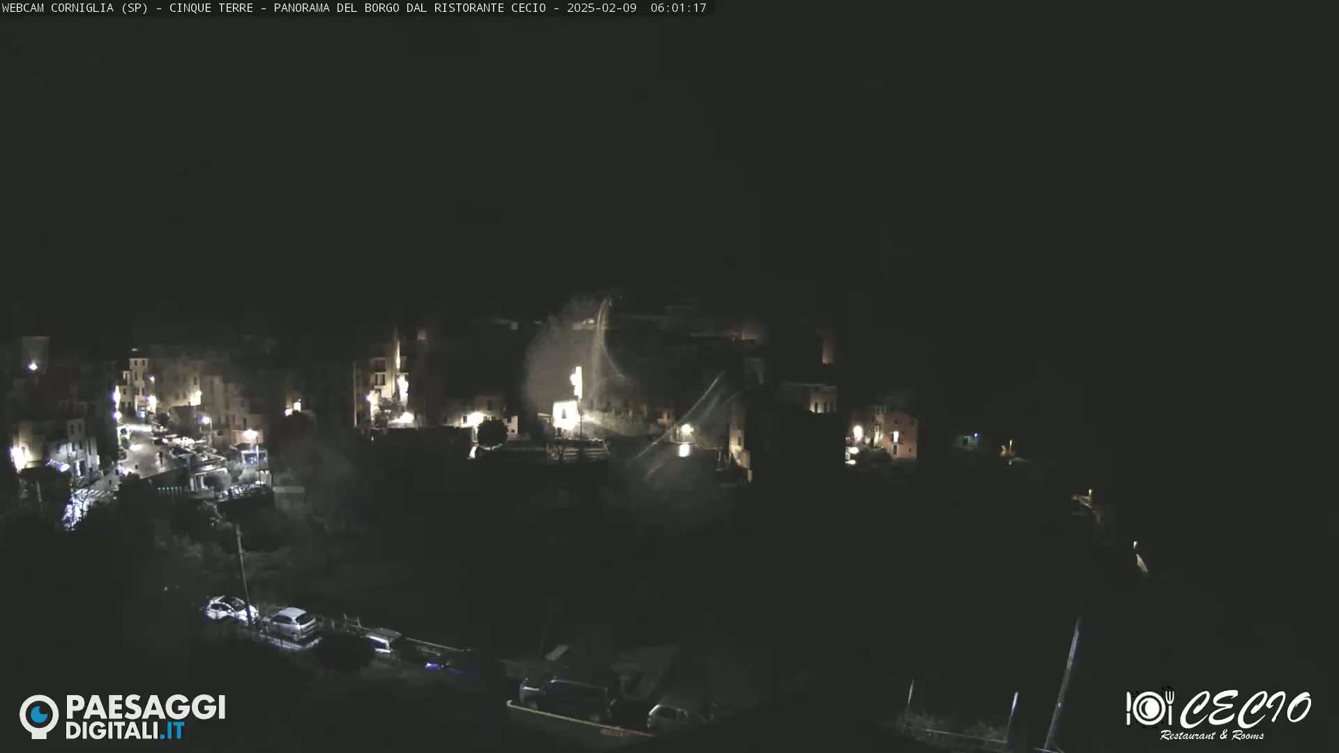 A nighttime aerial view of a dimly lit town, possibly in a mountainous region.