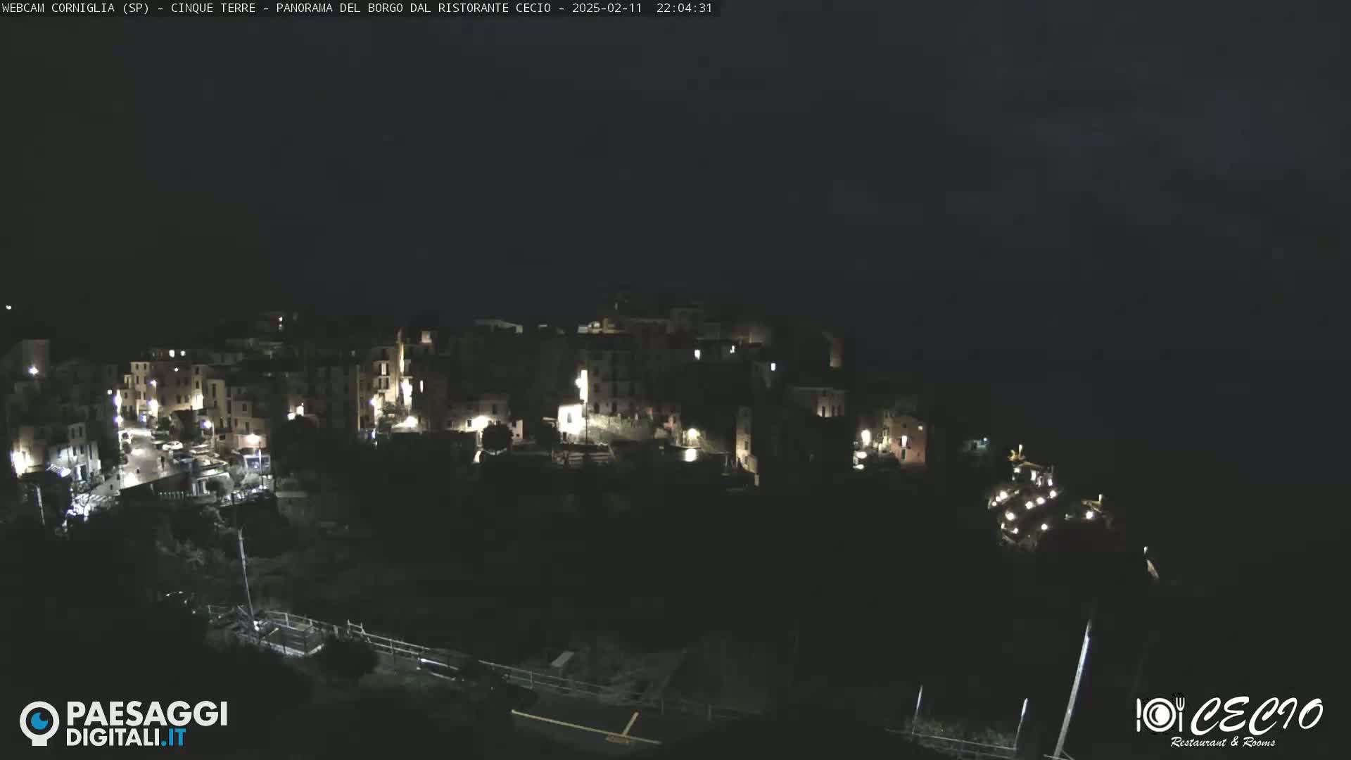 A nighttime aerial view of a small, dimly lit village clinging to a hillside.