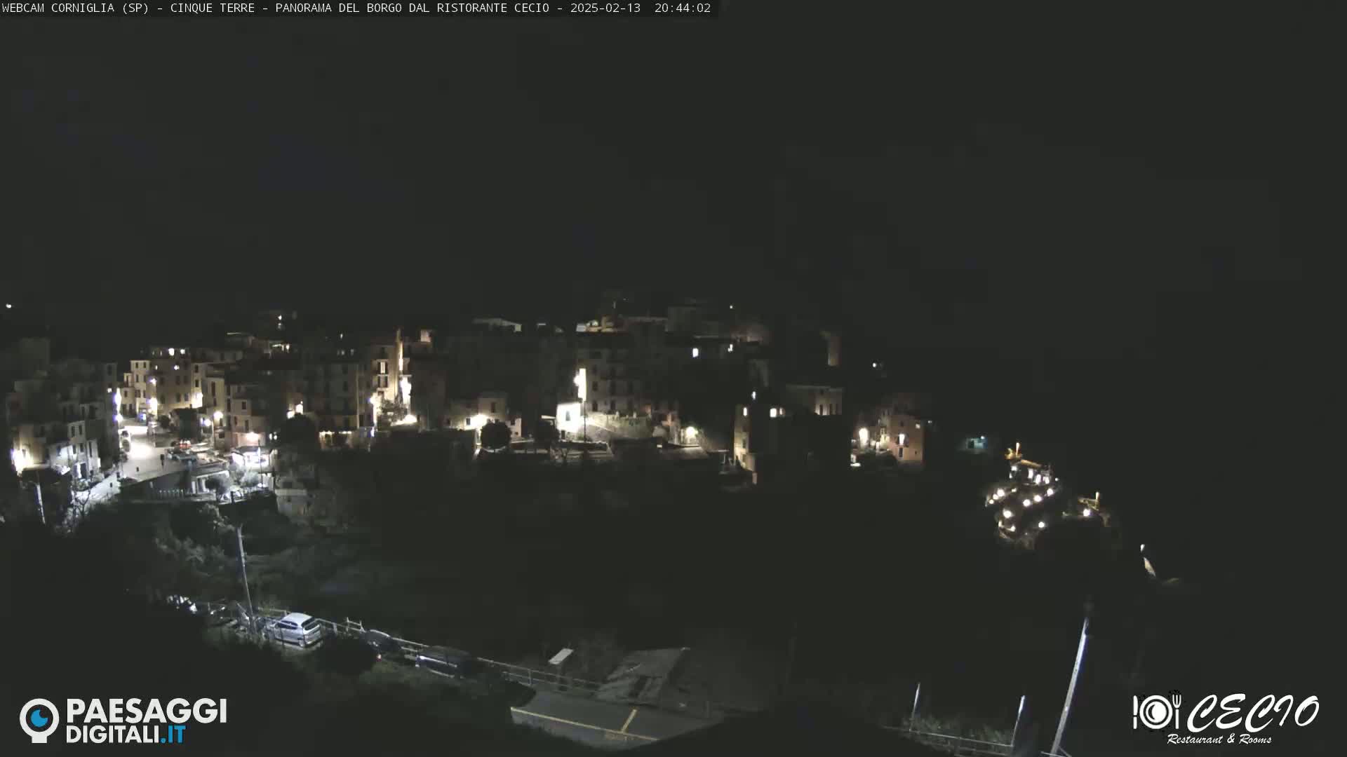 A nighttime, high-angle view of a small, illuminated town nestled on a hillside.