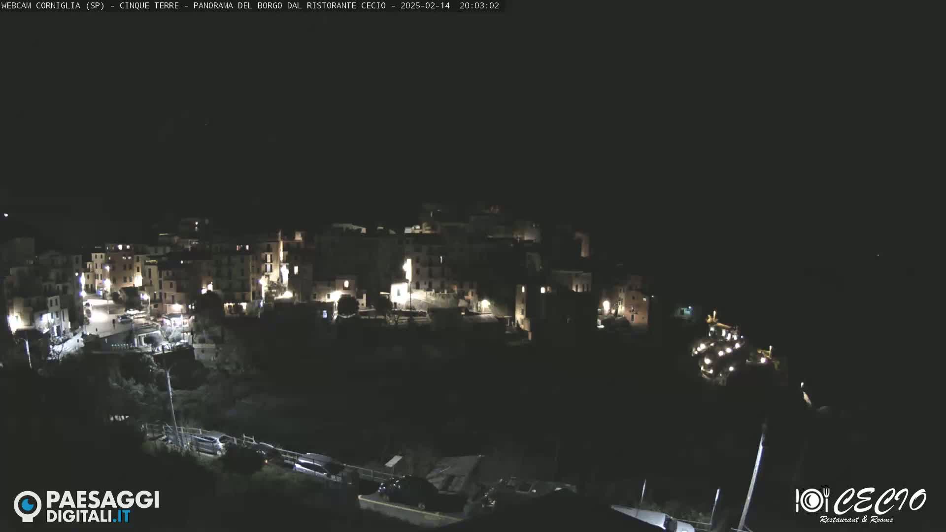 A nighttime, high-angle view of a small, illuminated town nestled on a hillside.