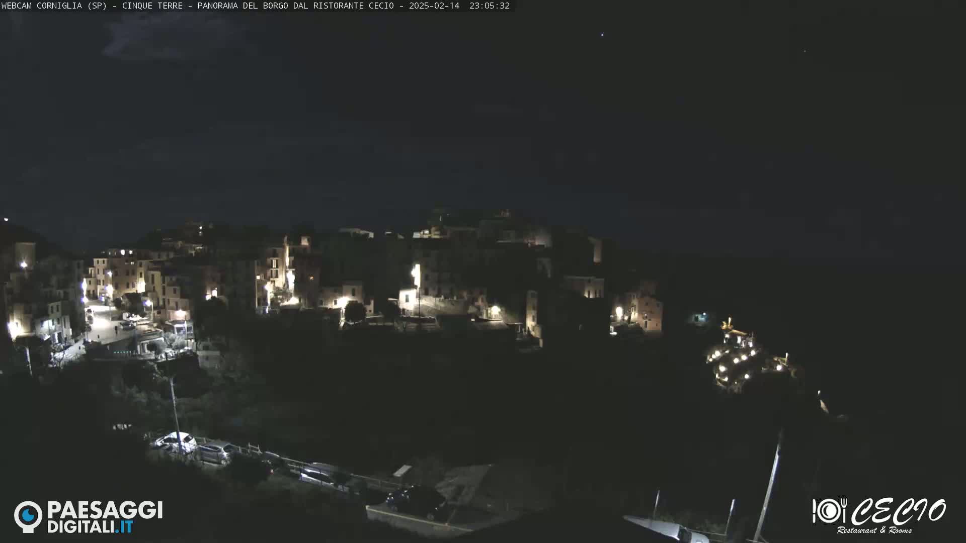 A nighttime view of a small, illuminated village nestled on a hillside under a clear, dark sky.