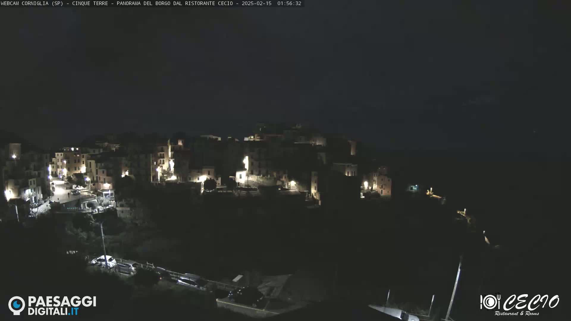 A nighttime, high-angle view of a small, illuminated town nestled on a hillside.