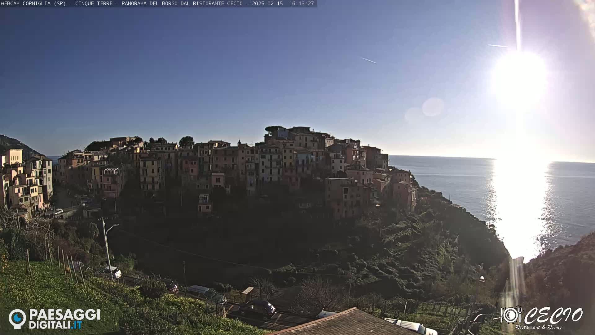 A sunny day overlooking a coastal town of colorful buildings nestled on a hillside, with a calm sea stretching to the horizon.