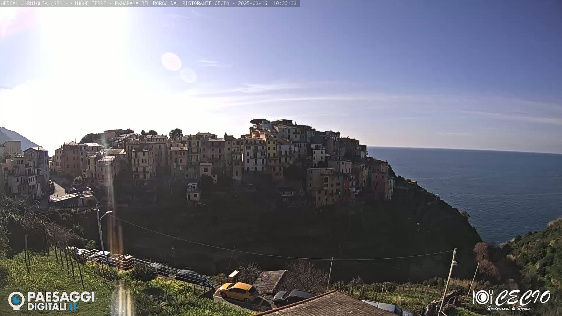 A sunny day reveals a coastal town built into a hillside overlooking a calm ocean.