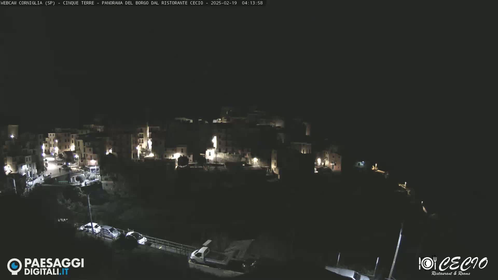 A nighttime, aerial view of a small, dimly lit town nestled on a hillside.