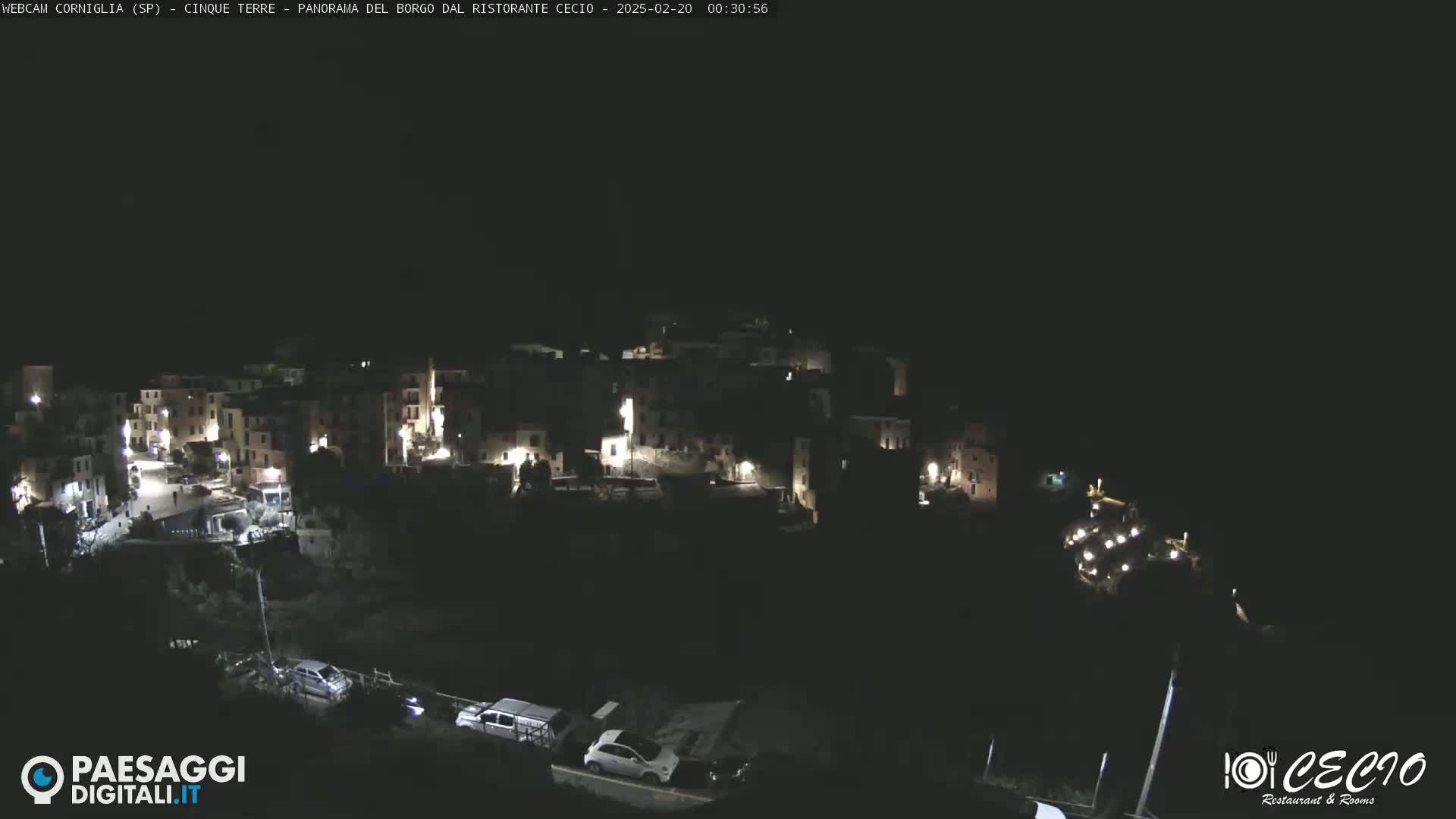 A nighttime, high-angle view of a small, dimly lit town nestled on a hillside.