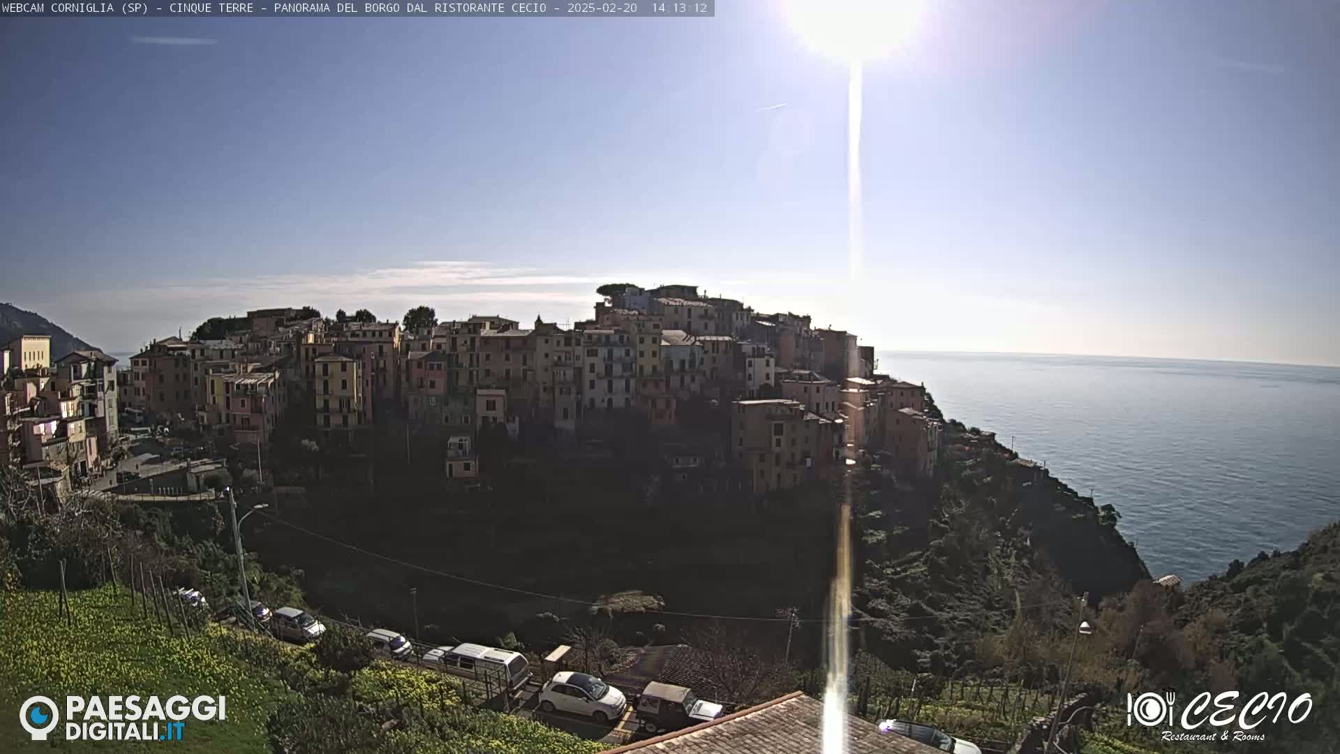 A sunny day overlooking a colorful hillside village perched on a cliff overlooking a calm sea.
