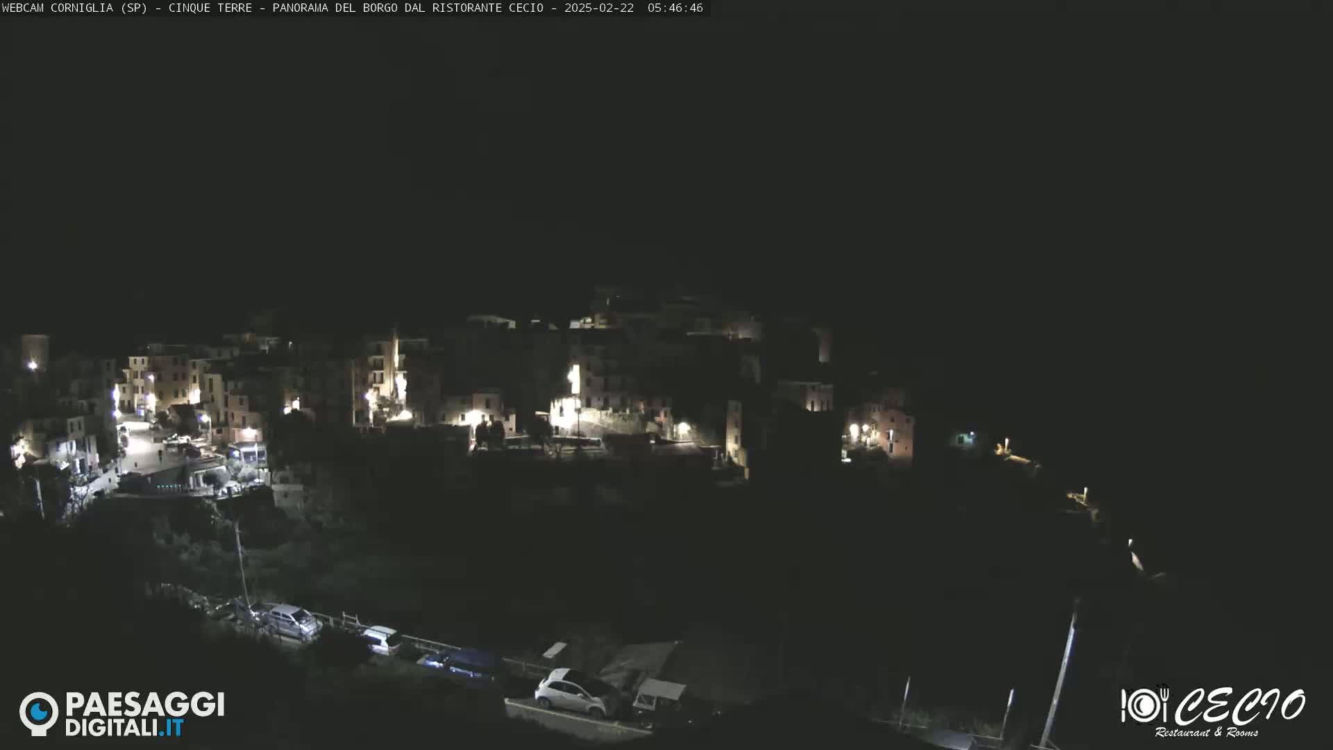 A nighttime, high-angle view of a small, illuminated town nestled on a hillside.