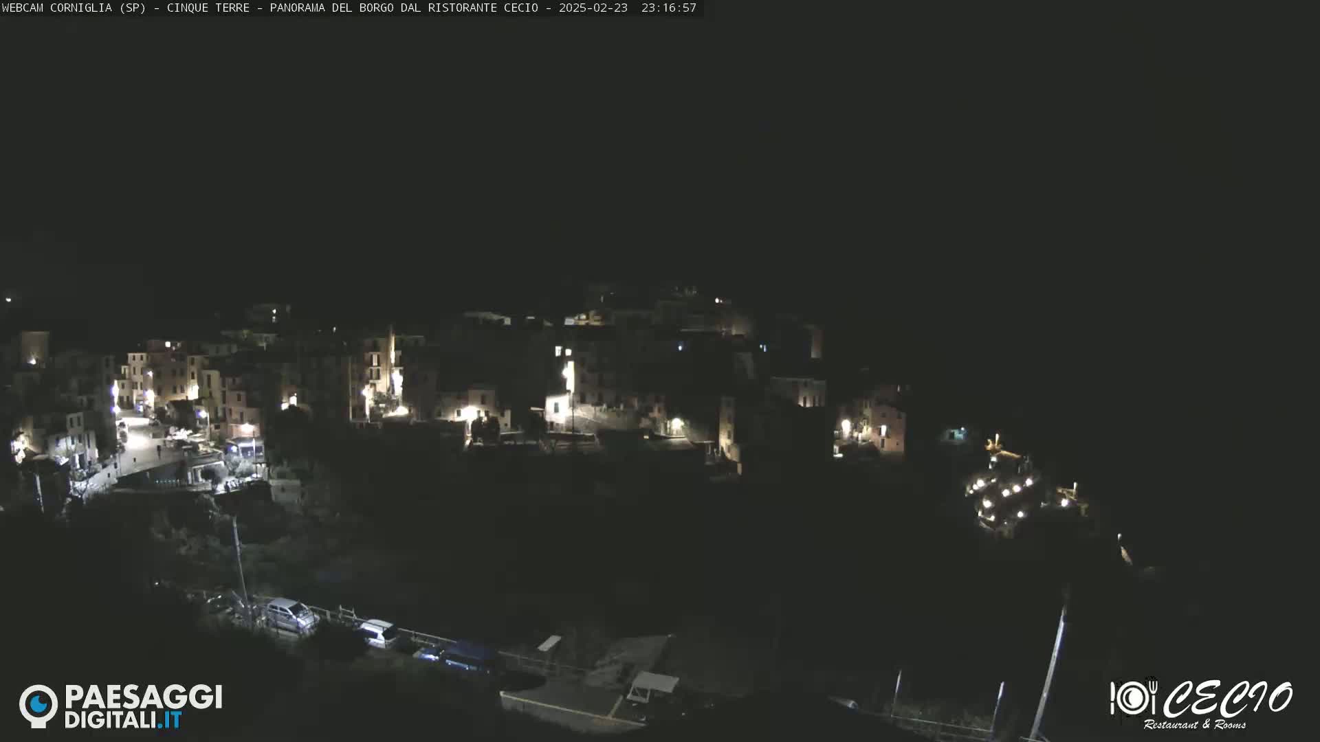 A nighttime view of a small, illuminated village nestled on a hillside.