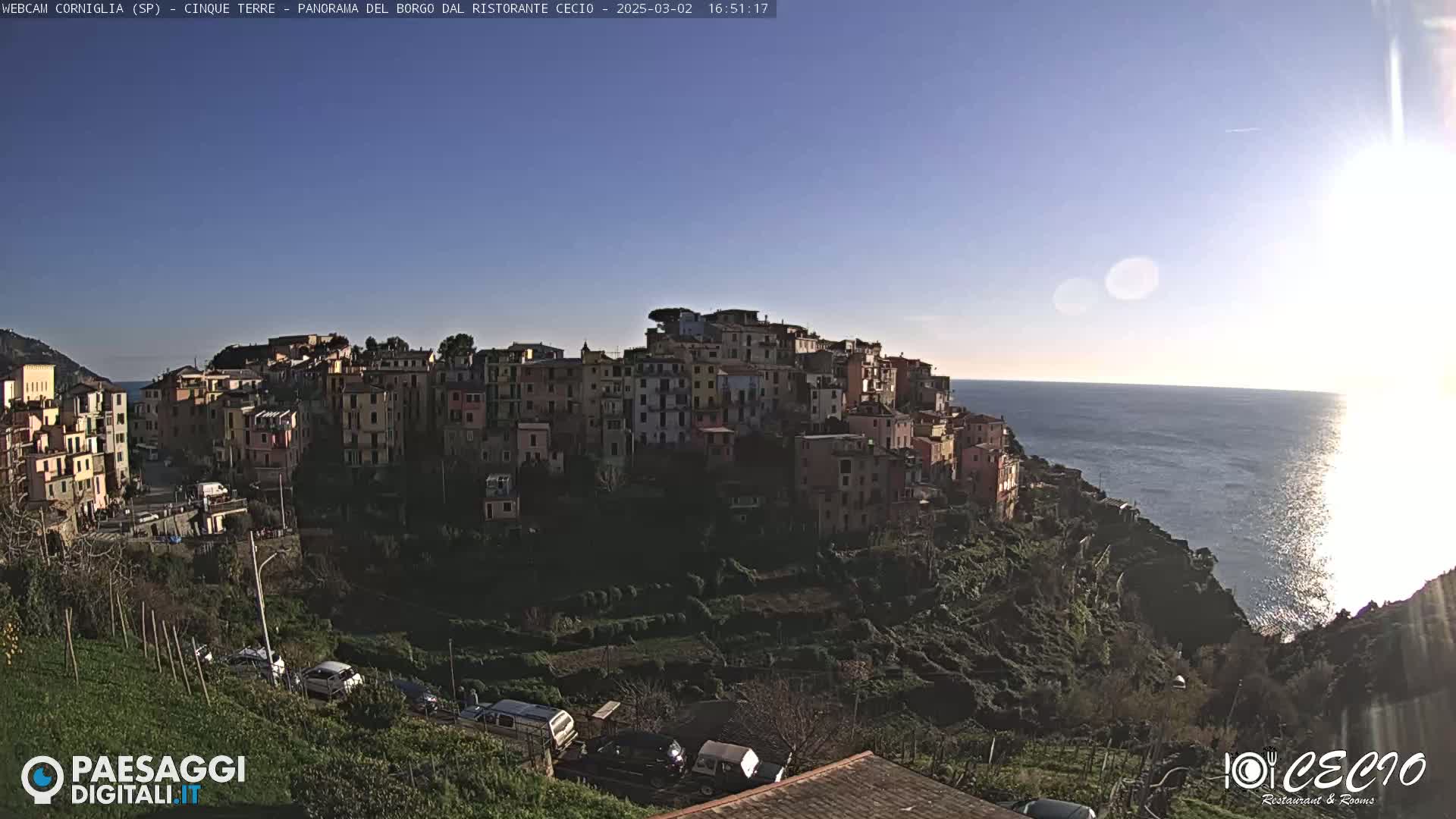 A coastal town built into a hillside overlooks a calm sea under a clear, sunny sky.