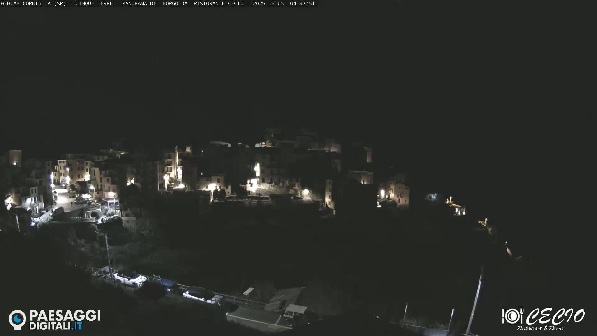A nighttime, aerial view of a small, illuminated town nestled on a hillside.
